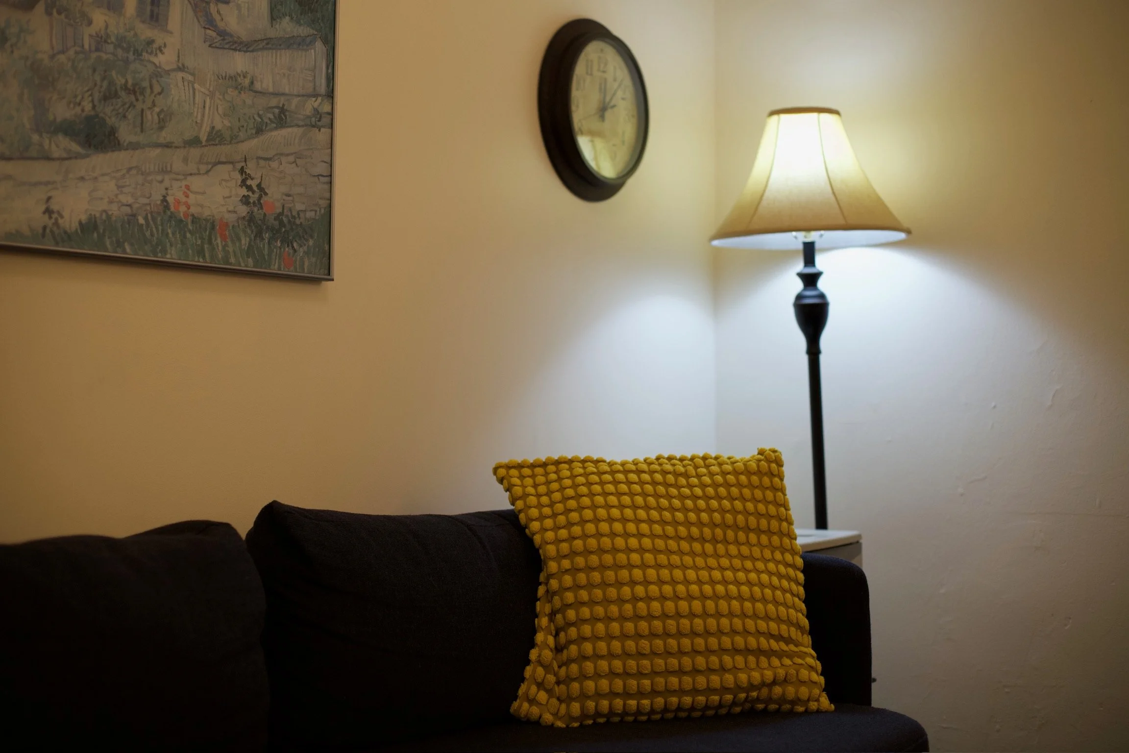 a photo of Leya's office with a blue couch, yellow pillow, and calm lighting