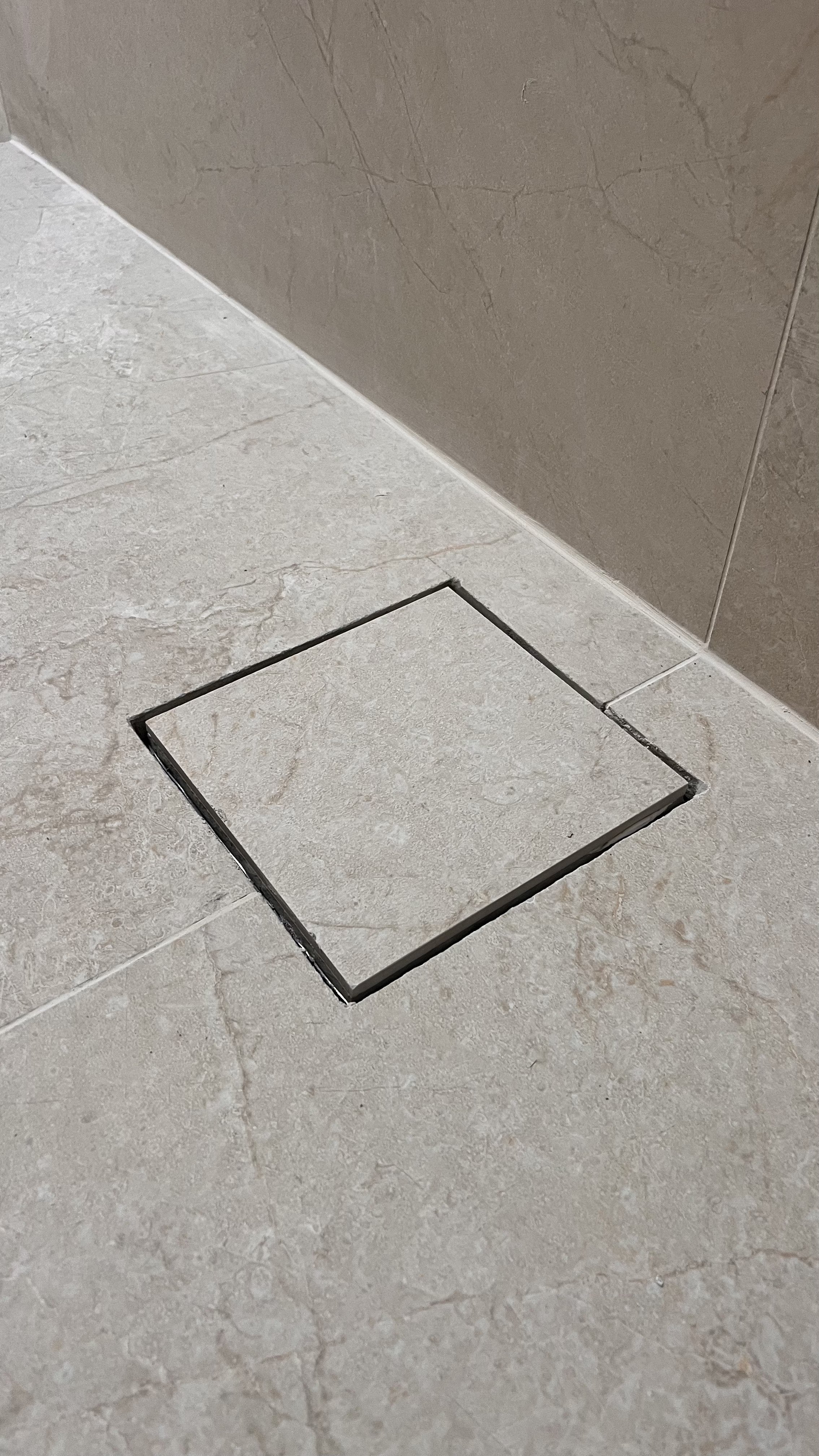 Rejunte de piso de banheiro ao redor de uma abertura quadrada no chão.