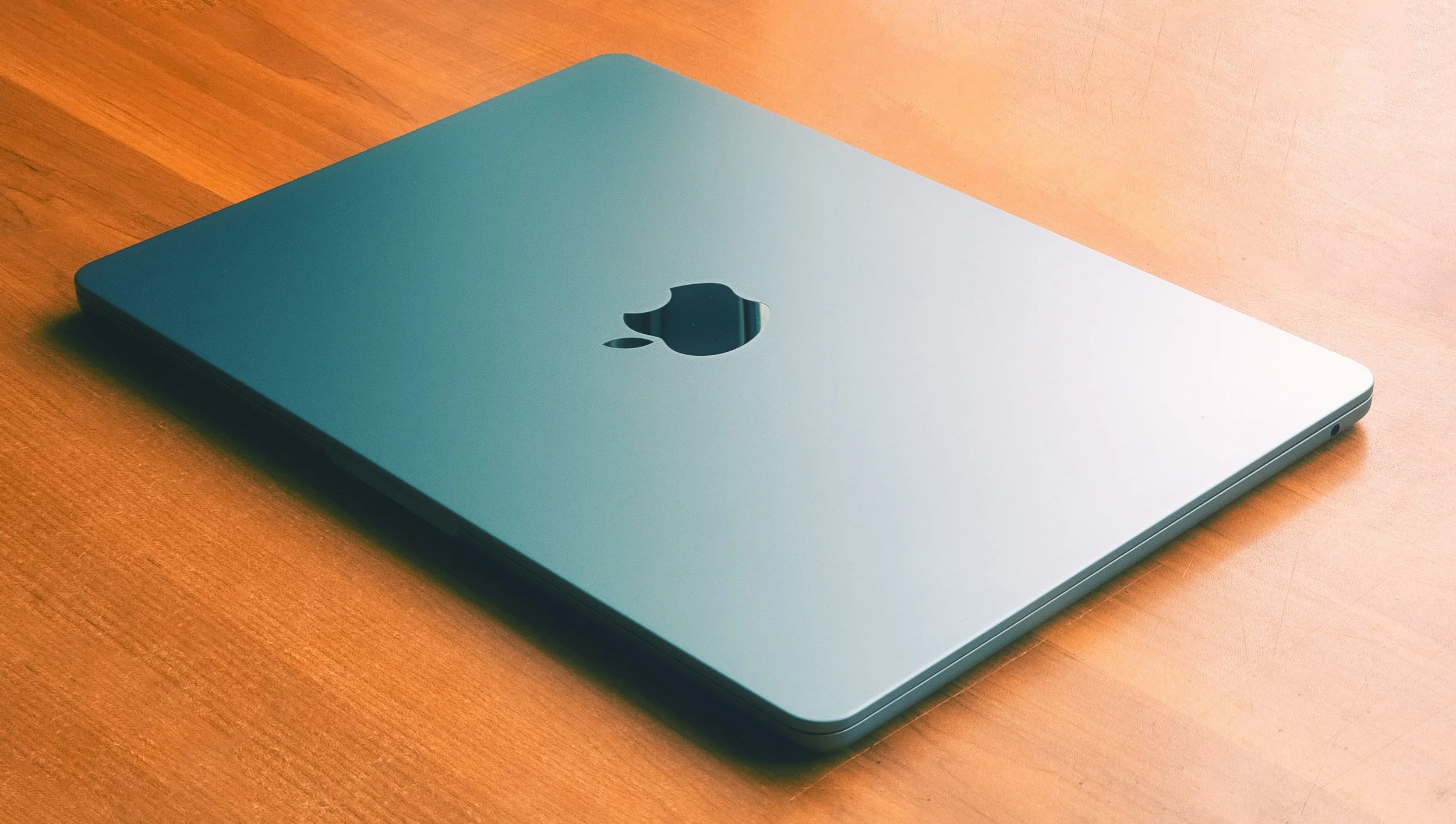 Silver Apple MacBook laptop closed on wooden table.