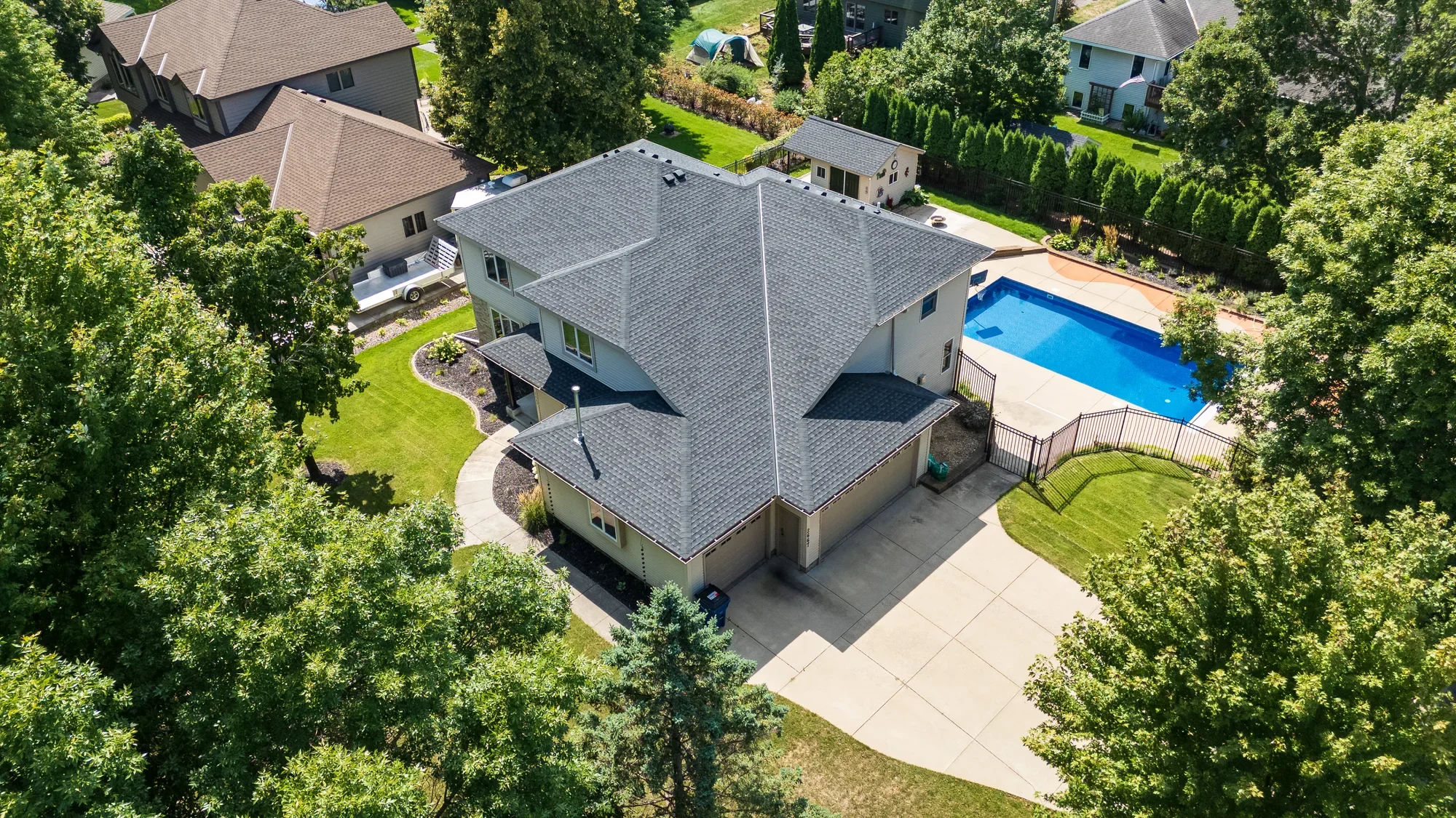 Wide aerial photograph of a lakeside property, pool and surrounding landscape