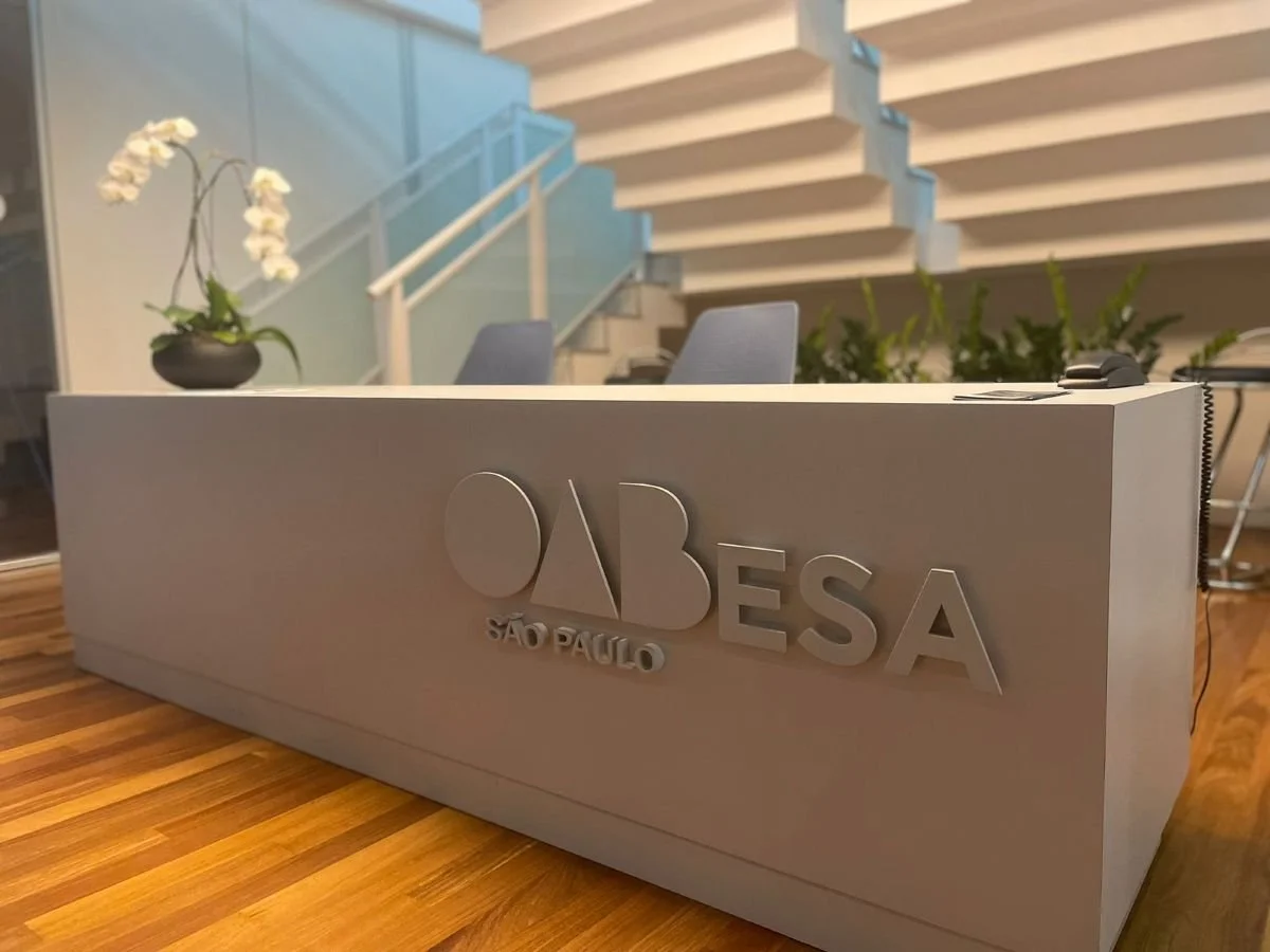 Recepção com placa de sinalização do OAB São Paulo, mesa de atendimento com telefone e decoração de flores orquídeas