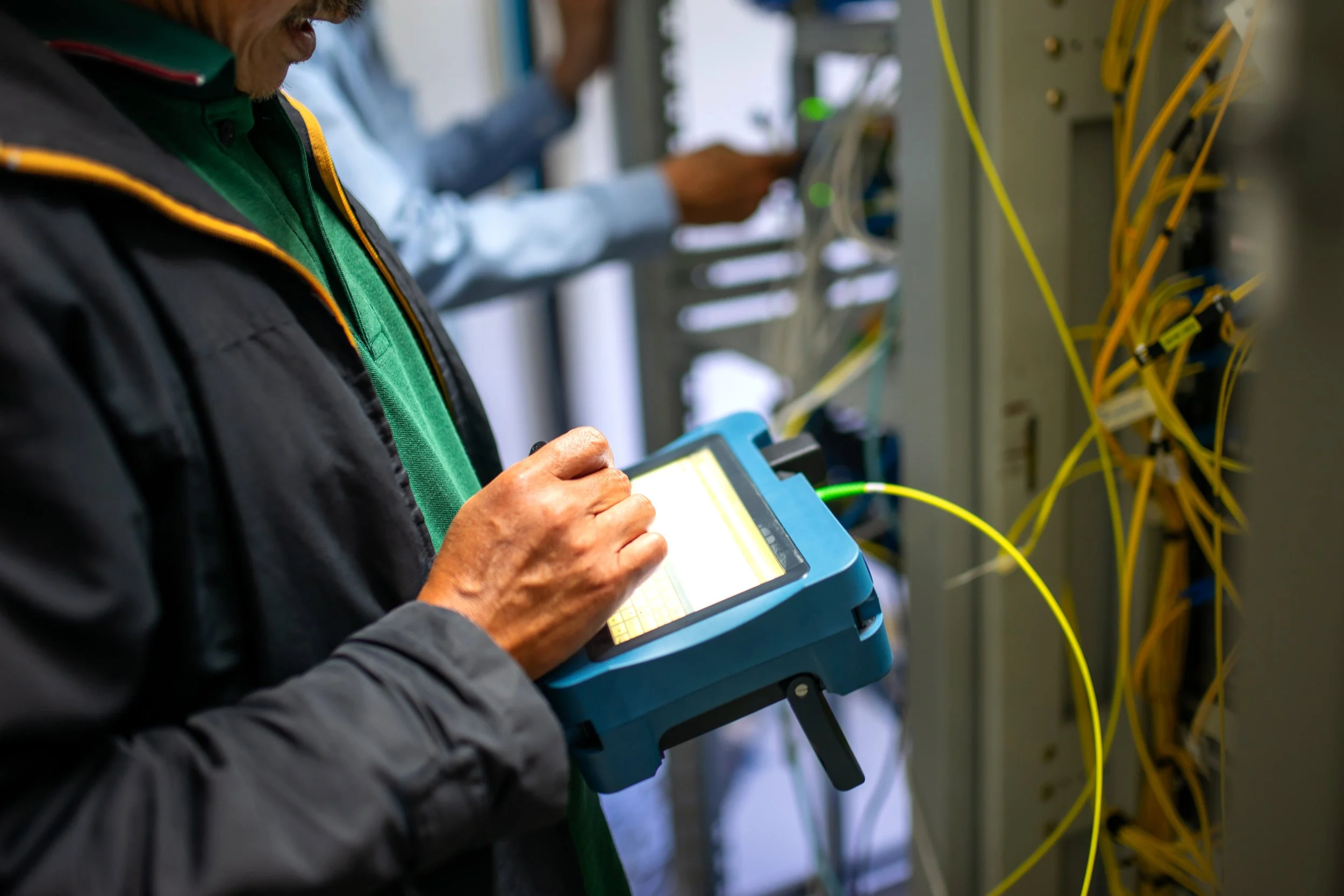 A technician running optical tests at a fiber patch panel