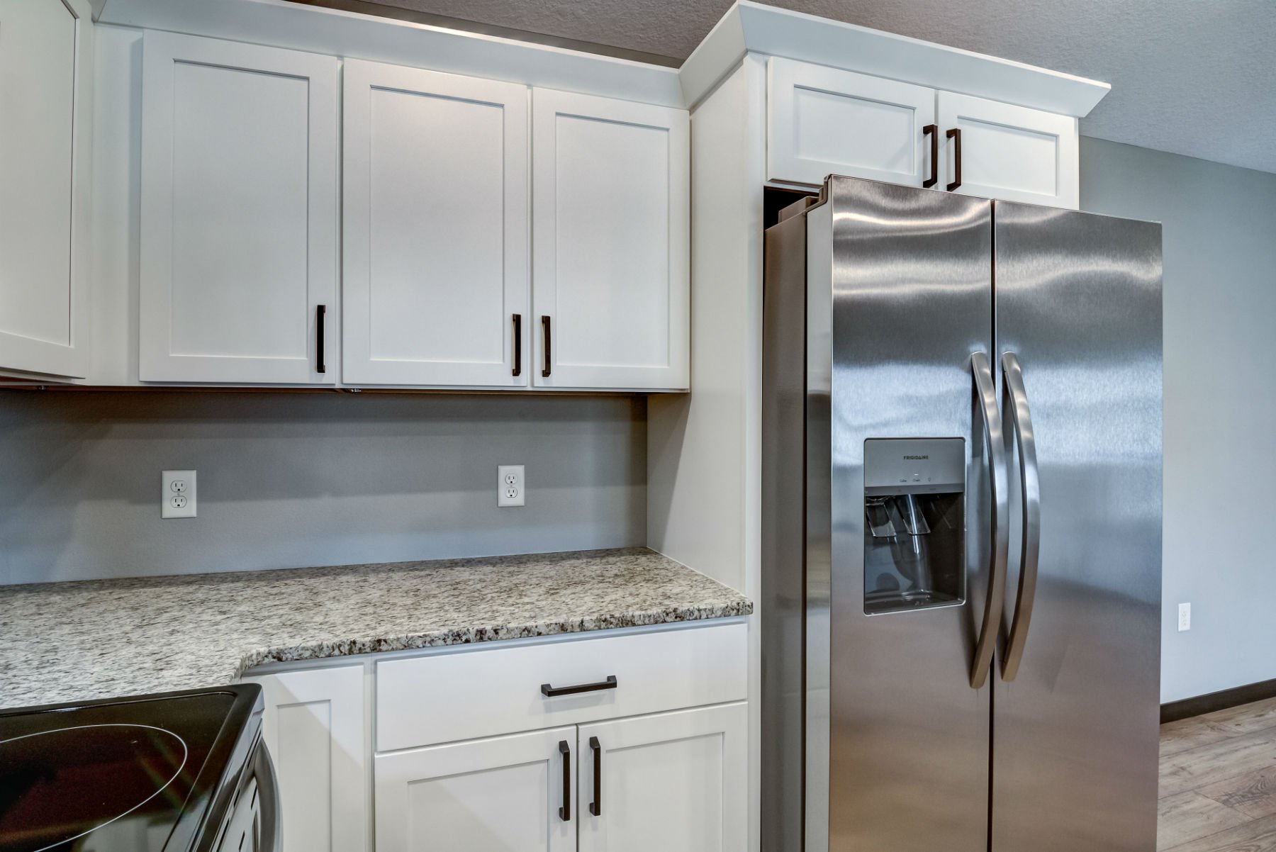 Kitchen with white cabinets, granite countertops, and a stainless steel refrigerator with double doors.