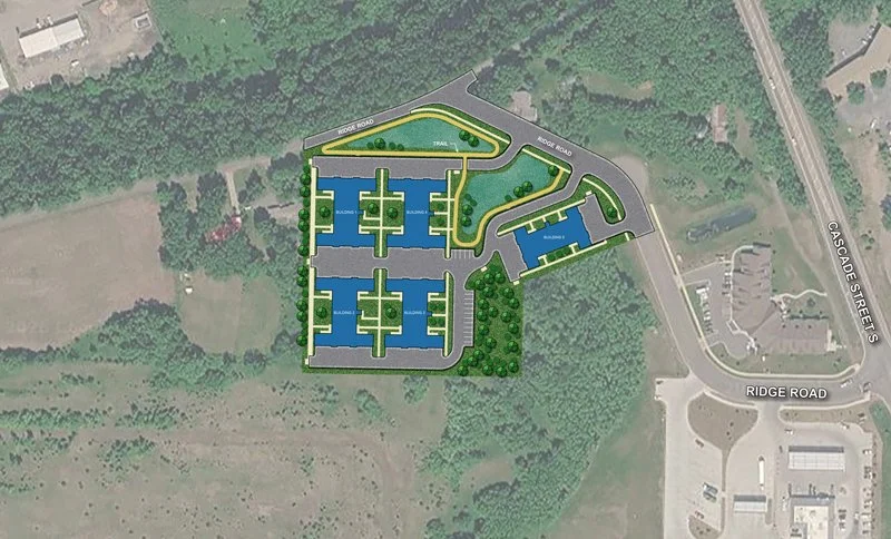 A site plan of an apartment complex showing multiple blue buildings, parking areas, roadways, and surrounding green landscape.