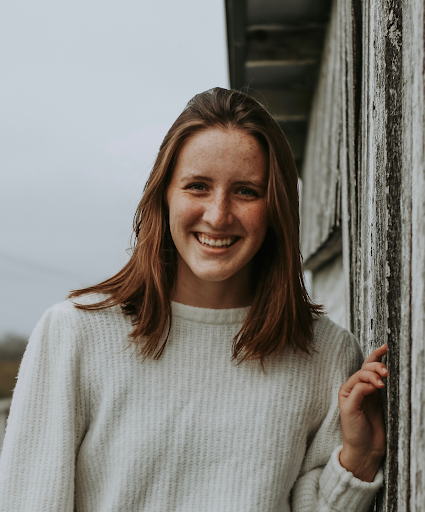 A headshot of a woman standing next to a barn door