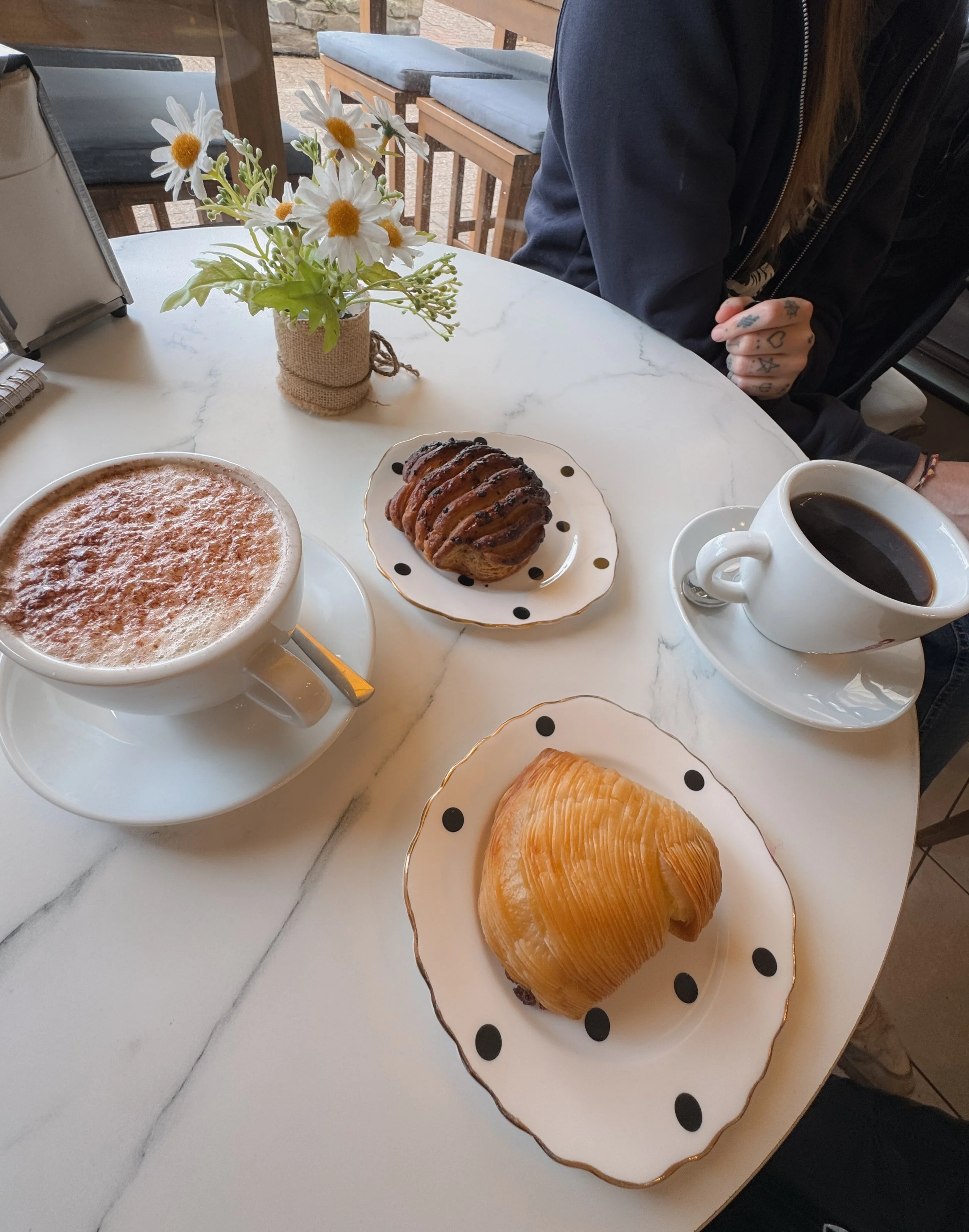 Coffe and cappuccino and flowers on a table in a bakery in Looe, Cornwall