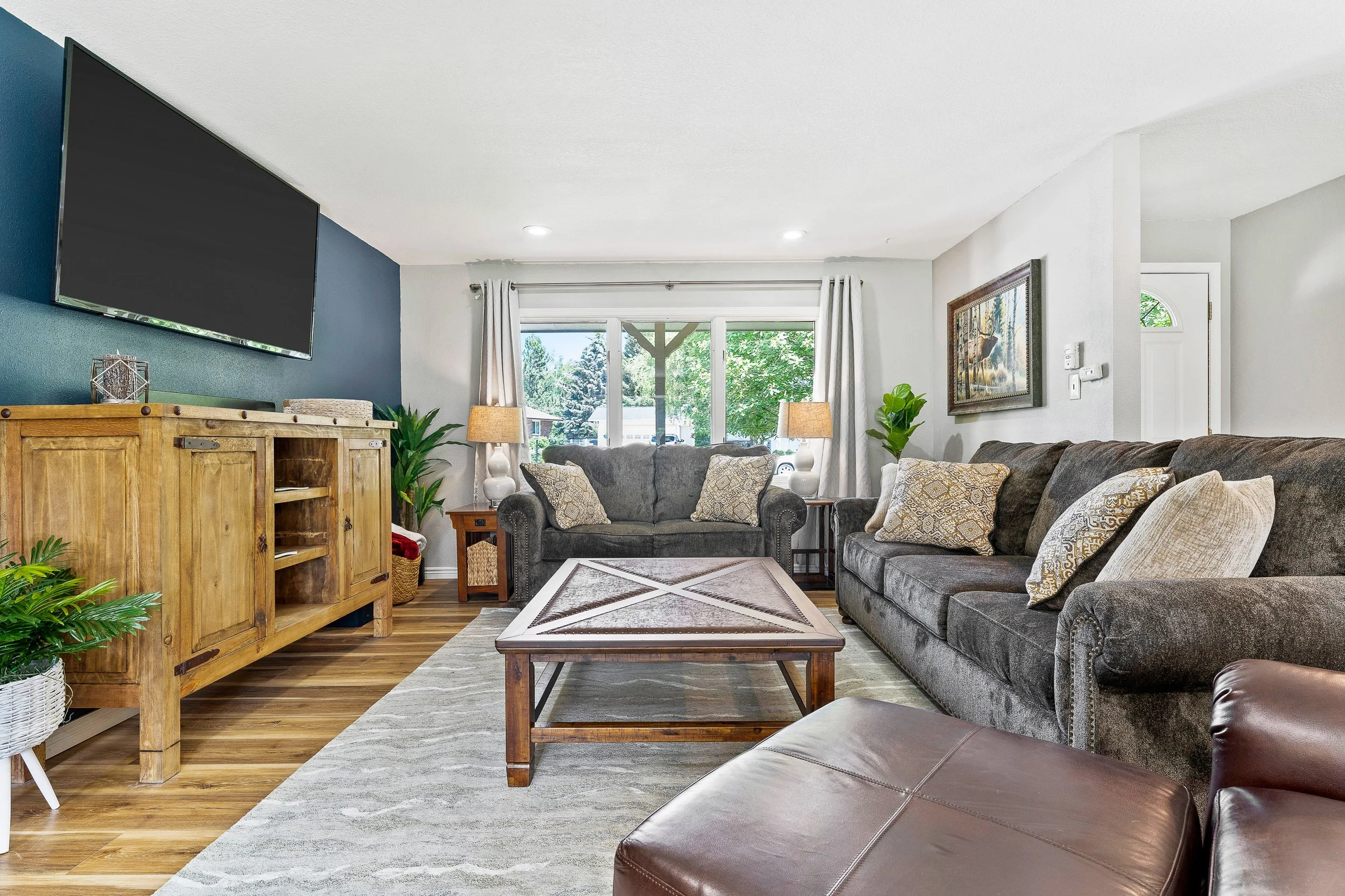 Open great room with navy accent wall, rustic barnwood cabinet, 65" smart TV, and queen sleeper sofa