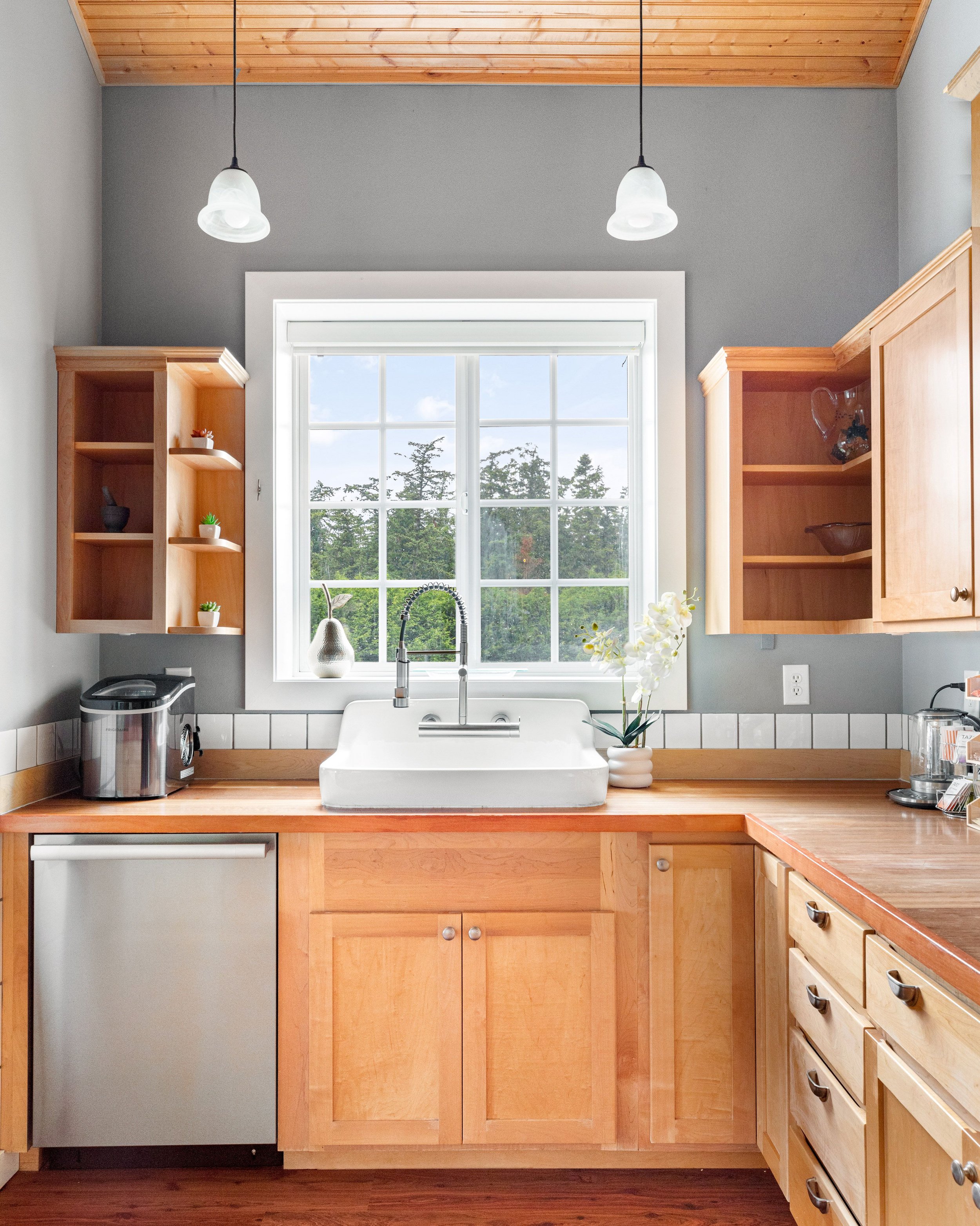 A fully equipped kitchen with farmhouse sink and garden window.