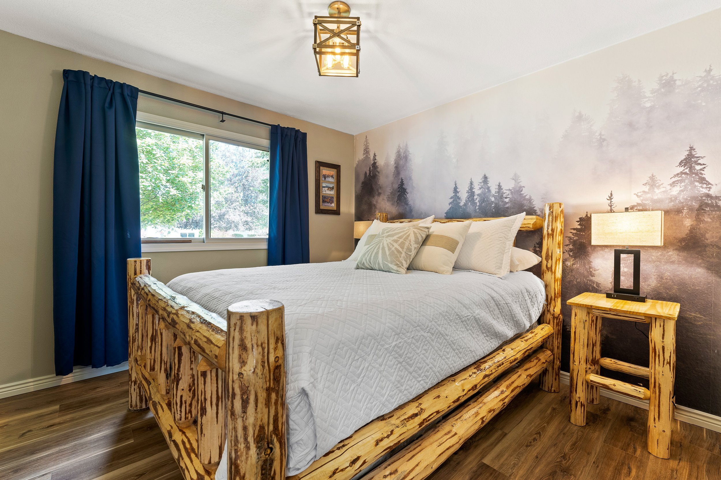 First bedroom with queen log bed and misty forest mural