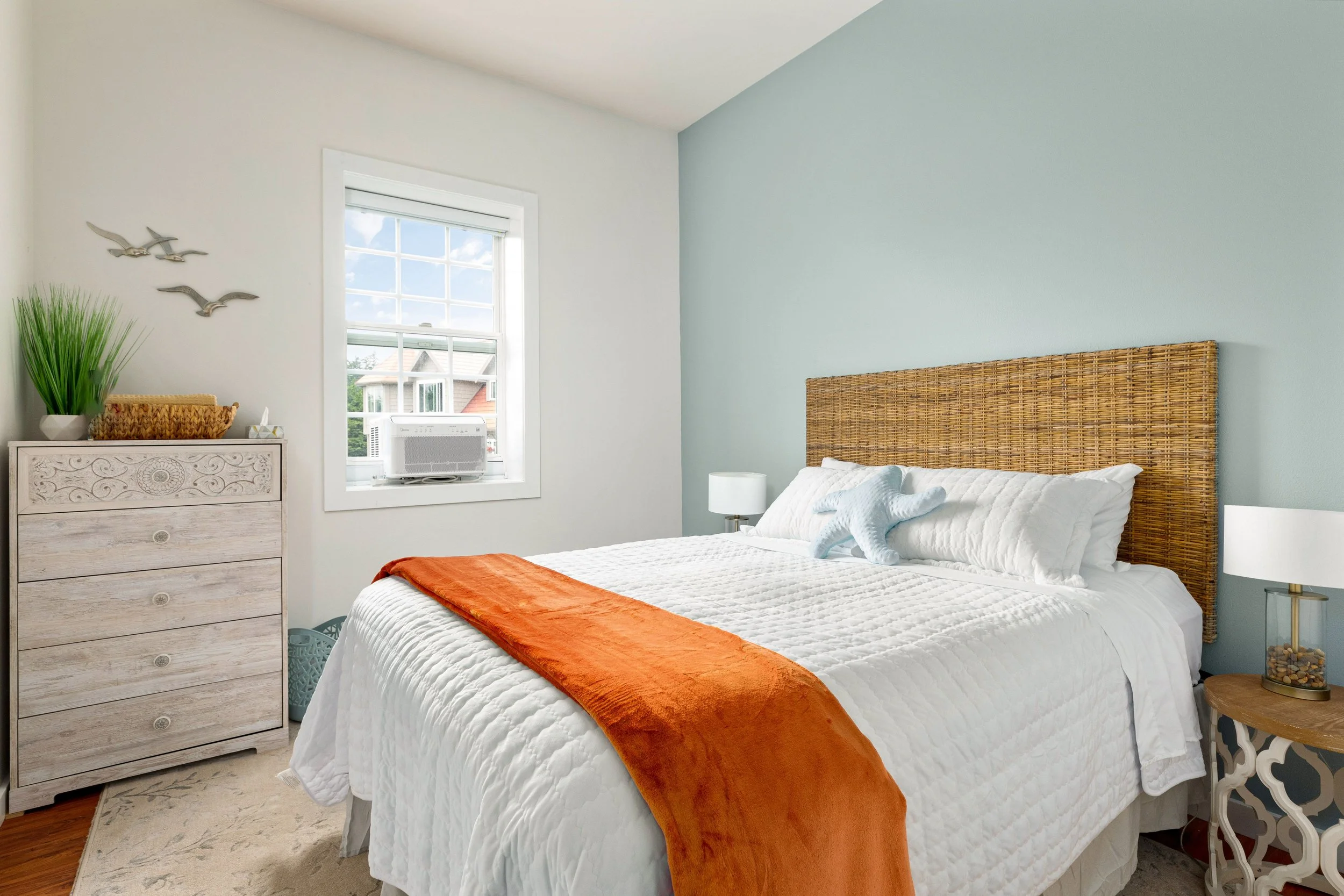 Queen bed, rattan headboard, and coastal charm.