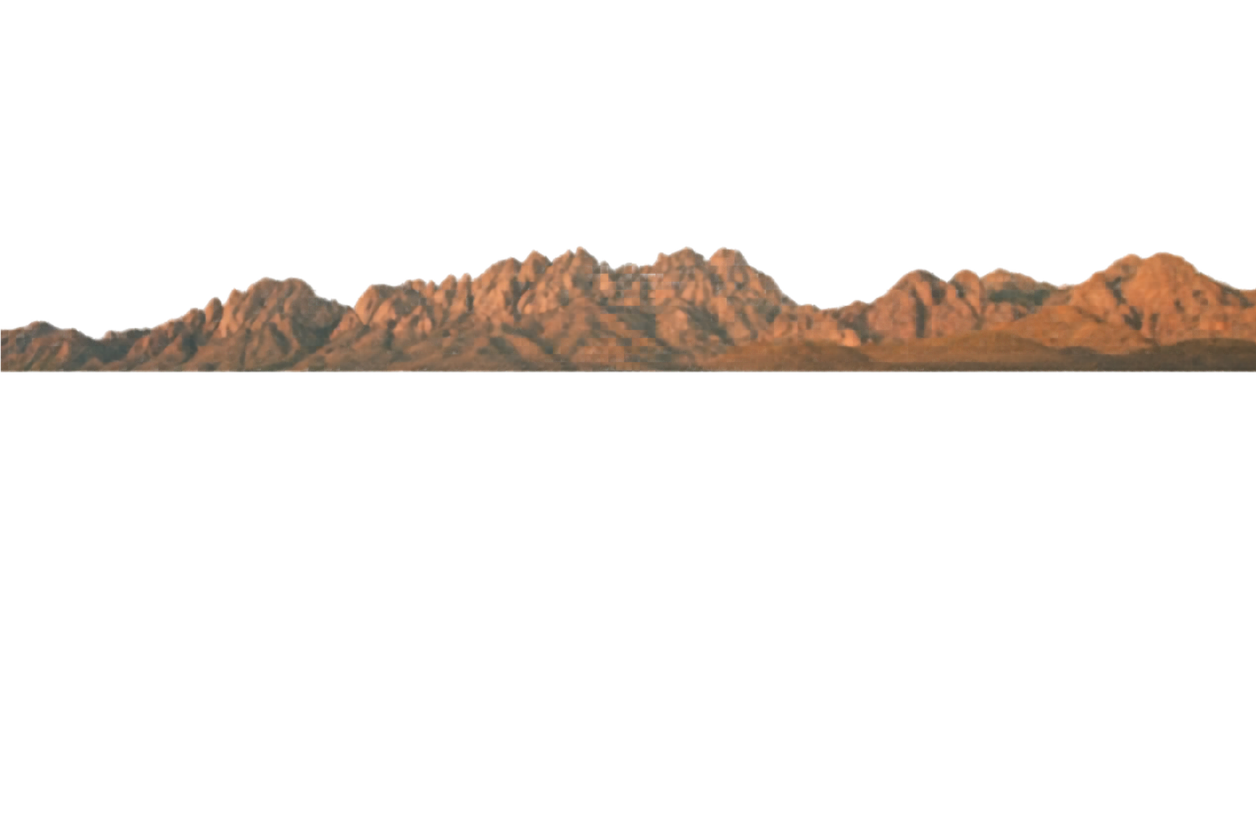 A desert landscape at sunset with rugged mountain peaks illuminated in warm orange light.