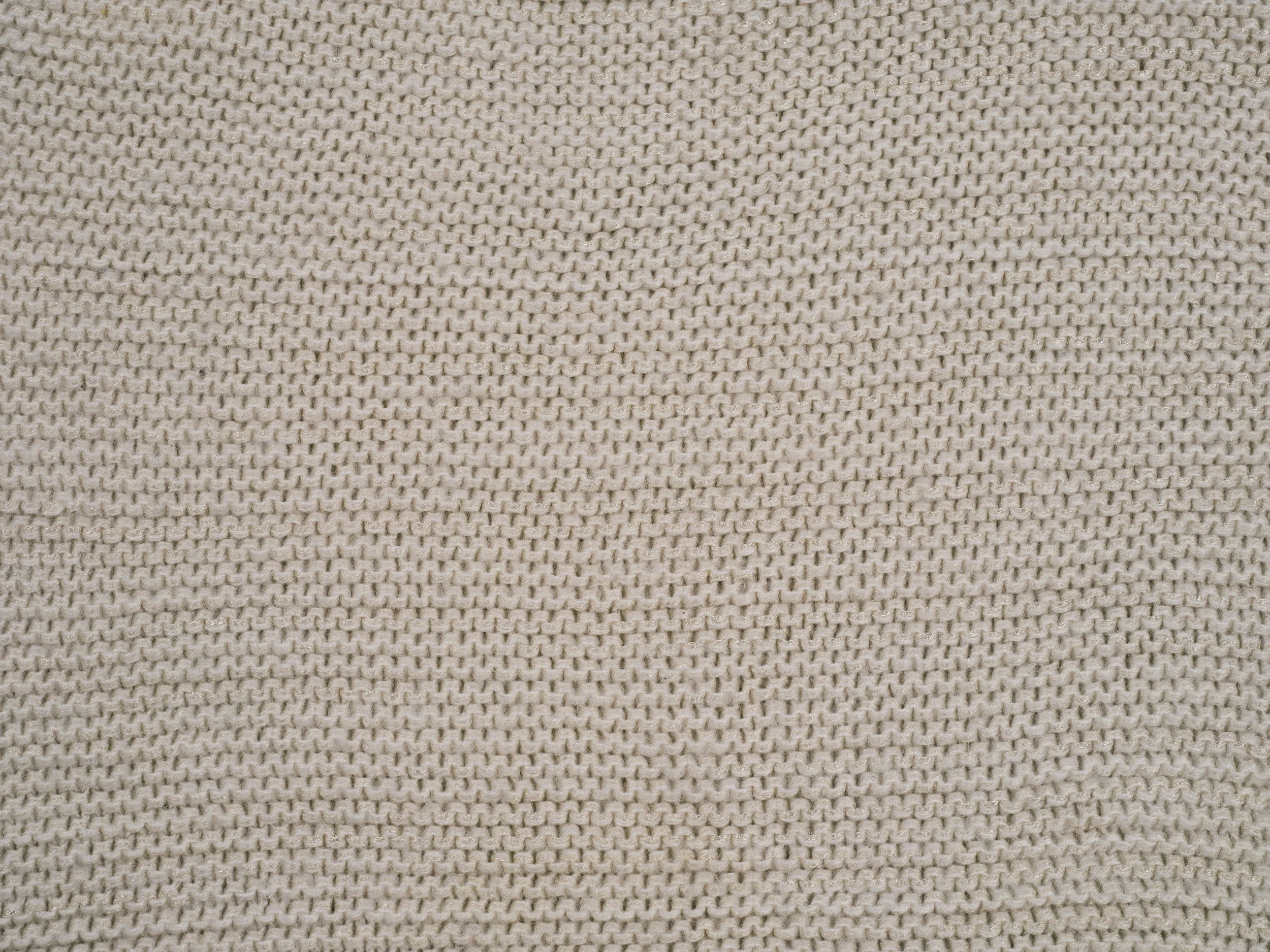 Close-up photograph of beige woven fabric with a repeating textured pattern.