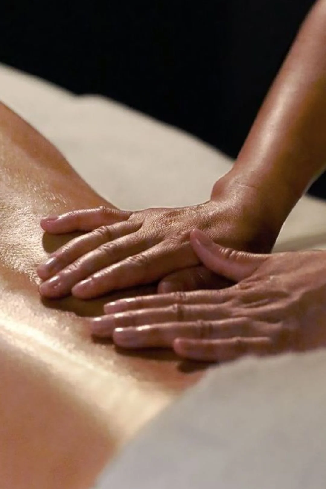 A person receiving a massage on their back, with visible concentration on the massage technique.