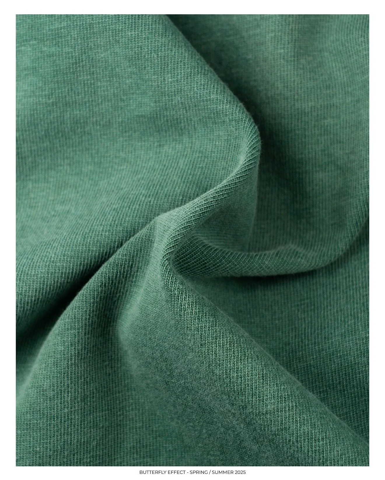 Close-up of green fabric with a textured, woven appearance, slightly wrinkled.
