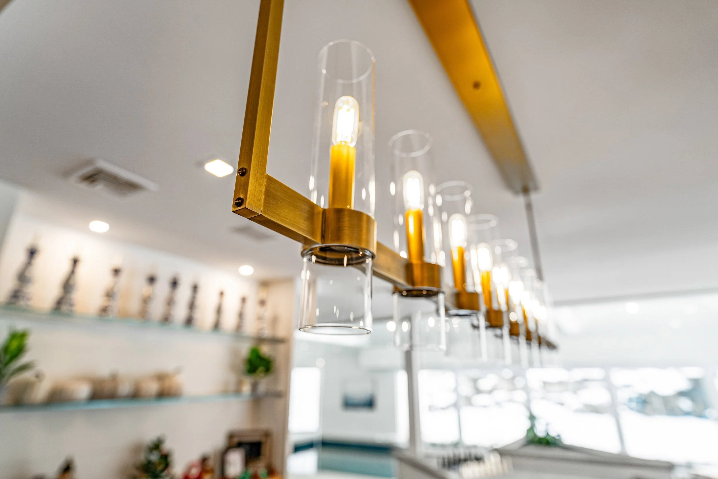 Close-up of modern pendant lights with clear glass shades and warm yellow bulbs hanging from a ceiling in a well-lit interior space.