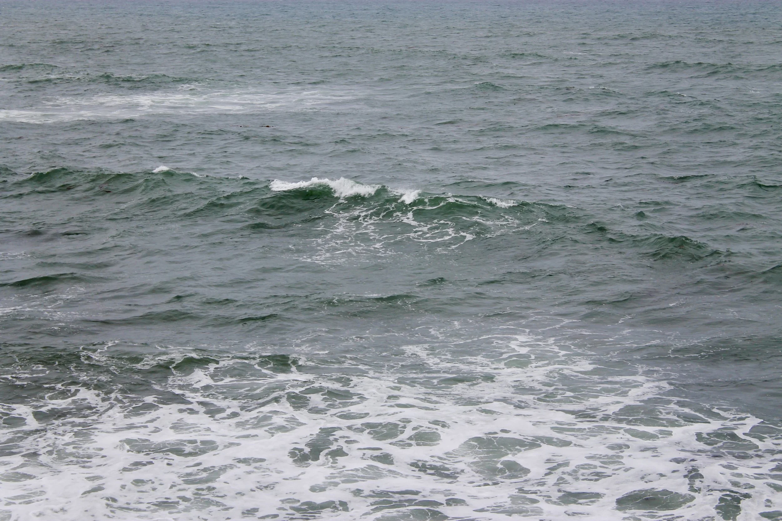 Ocean waves with some white foam, calm sea surface