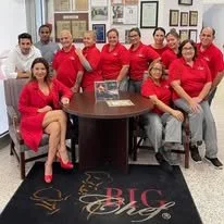 Group of people wearing red shirts sitting and standing around a round table in an office or meeting room