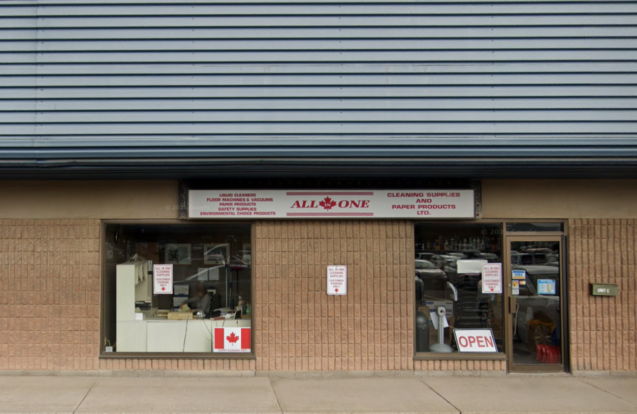 Storefront with a sign reading "All in One" that sells cleaning supplies, floor machines, vacuums, paper products, and environmentally friendly products, with an "Open" sign in the window.