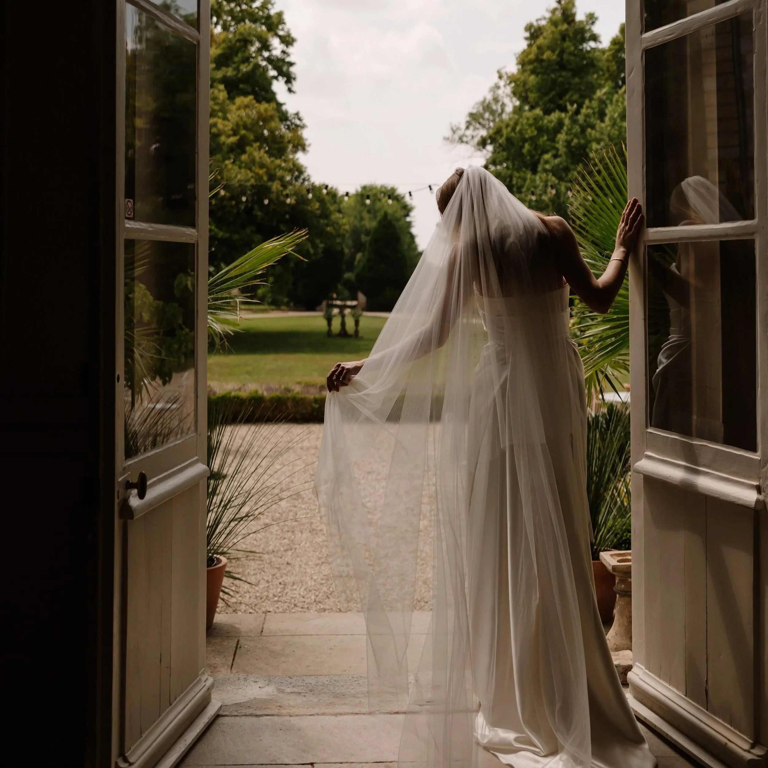 Bruid met een lange minimalistische sluier in een Frans kasteel tijdens een elegant en tijdloos editorial wedding moment