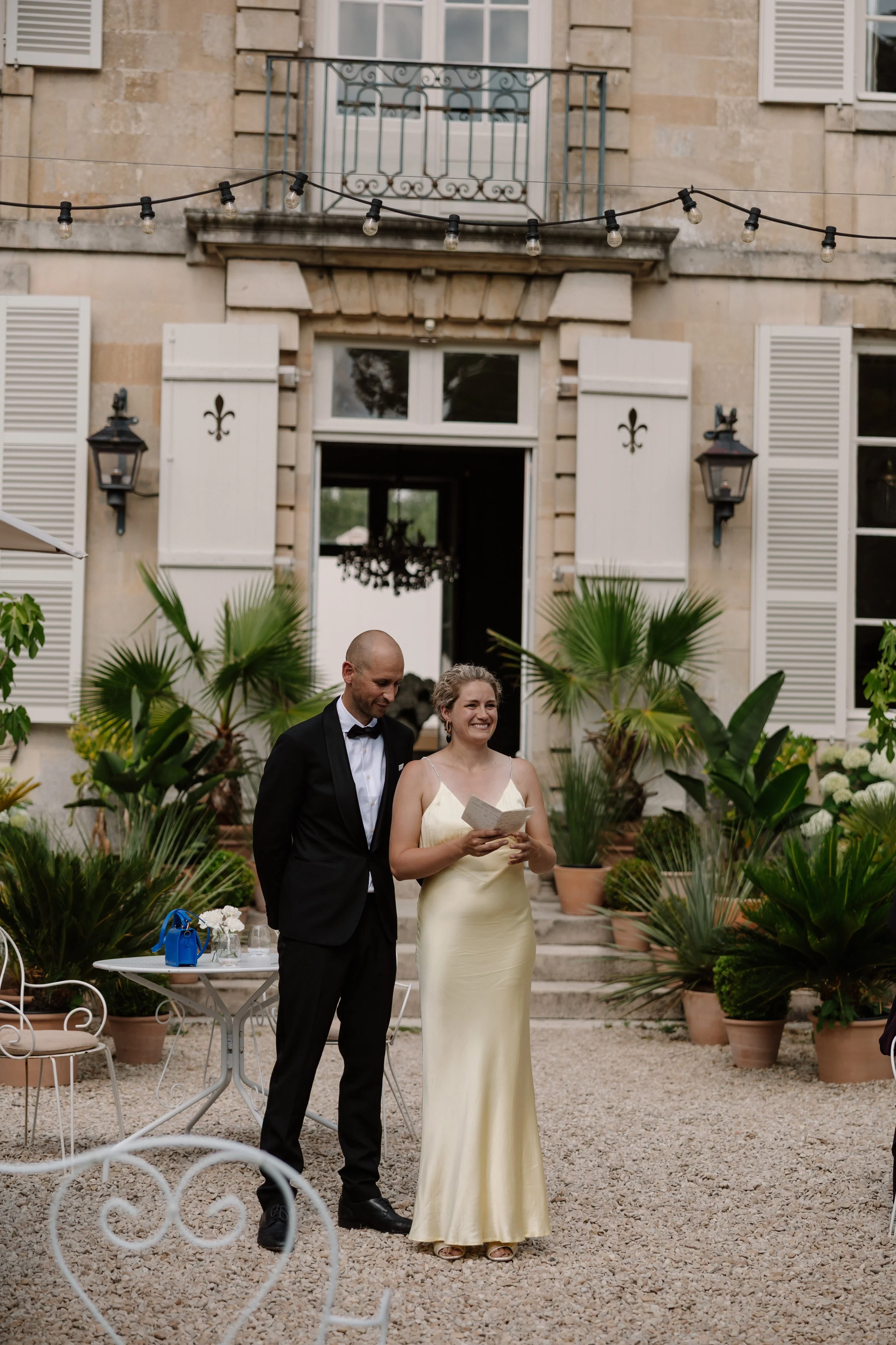 Gasten in black-tie brengen een toast uit op het bruidspaar buiten een Frans château tijdens een intieme en elegante editorial bruiloft