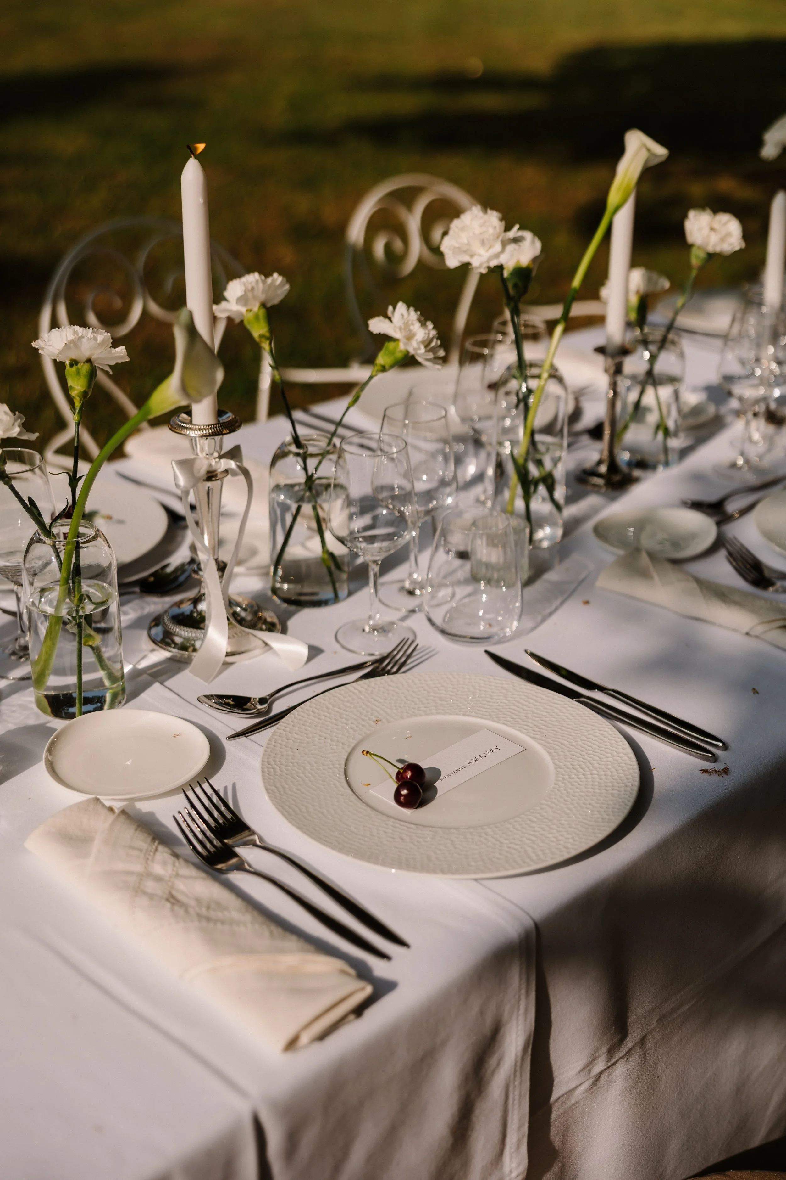 Quiet luxury tafelsetting met wit linnen, verfijnde tafeldekking, persoonlijke details en zacht kaarslicht voor een intieme viering
