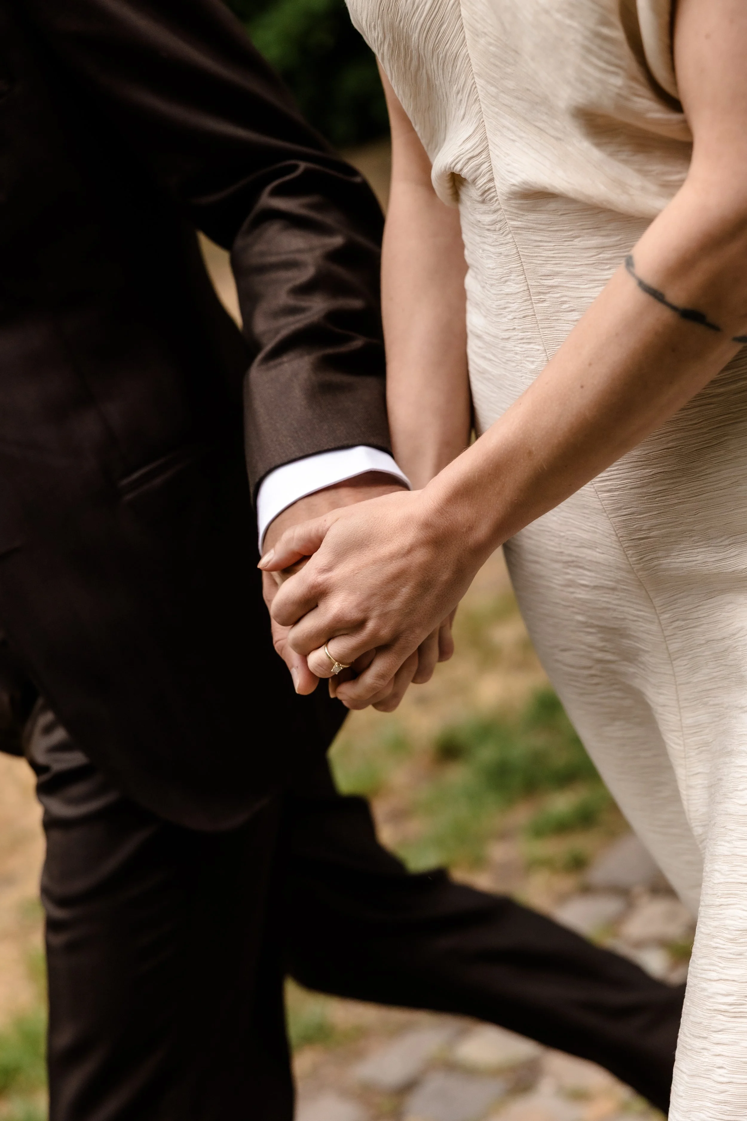 Bruidspaar dat elkaars handen vasthoudt tijdens een intieme ceremonie in Nederland, vastgelegd in een tijdloze editorial wedding stijl