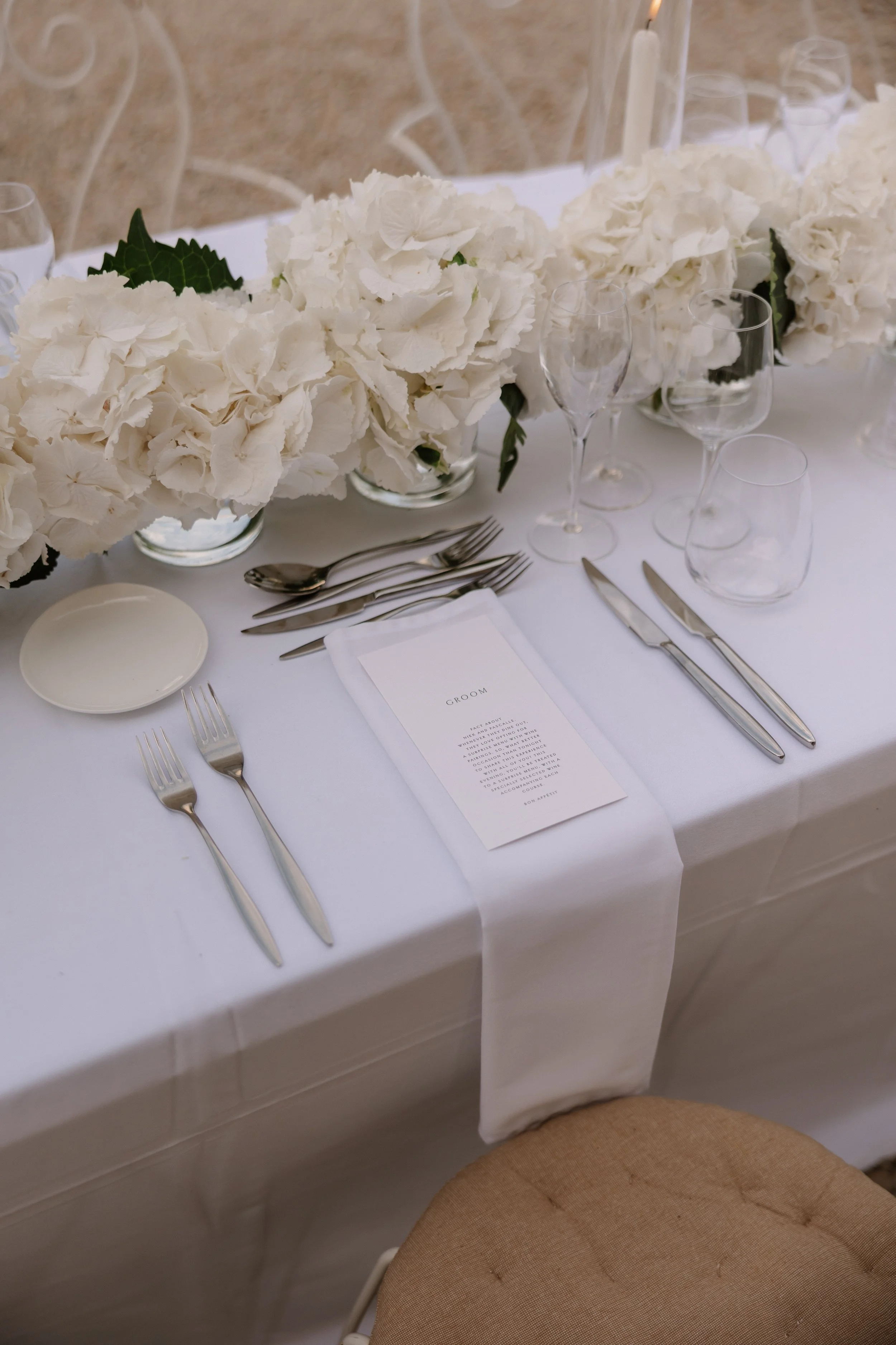 Tijdloze tafelaankleding met witte hortensias, verfijnde details, een persoonlijk naamkaartje en menu voor een elegante bruiloft