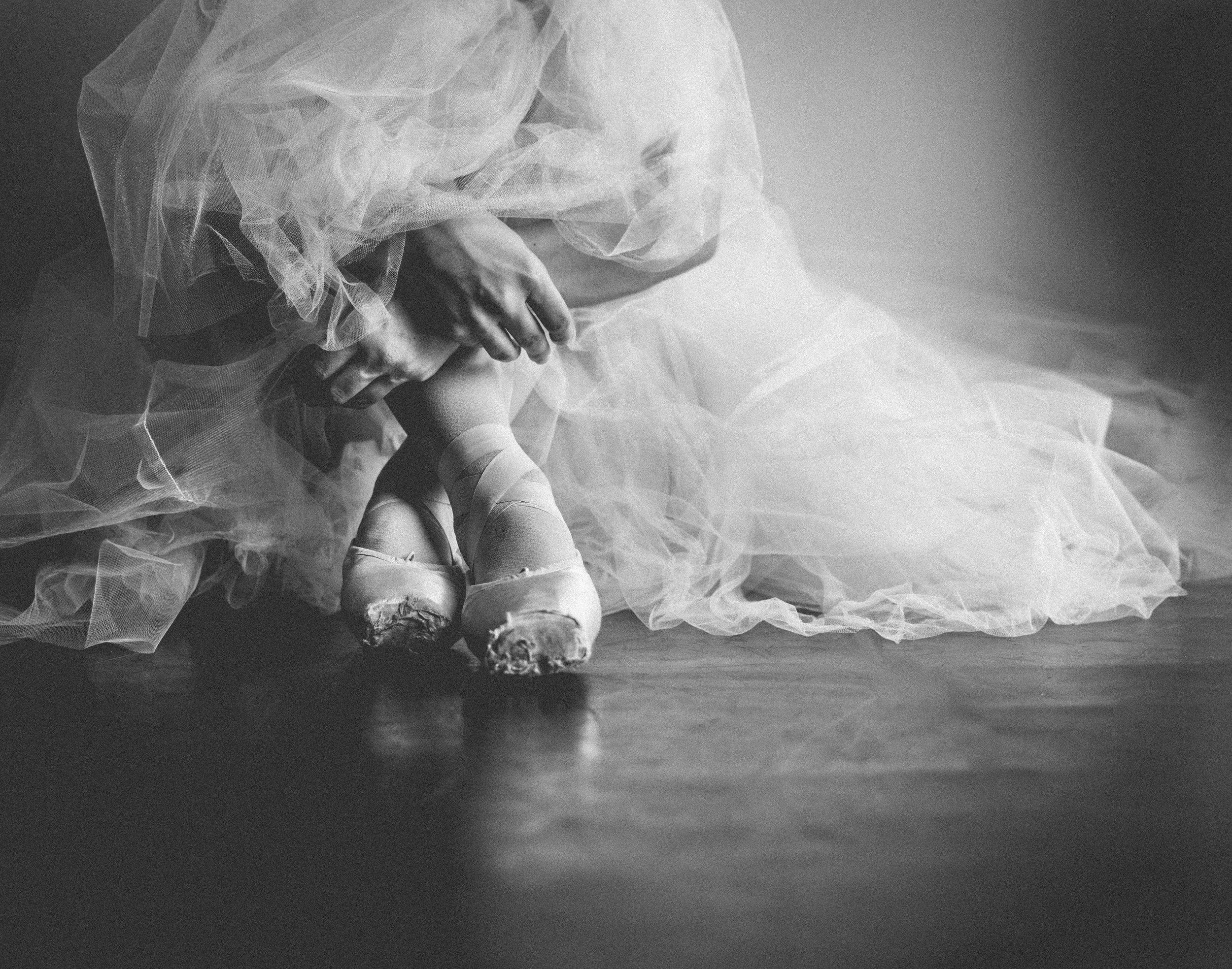 A person dressed in a romantic tutu sitting on the floor.