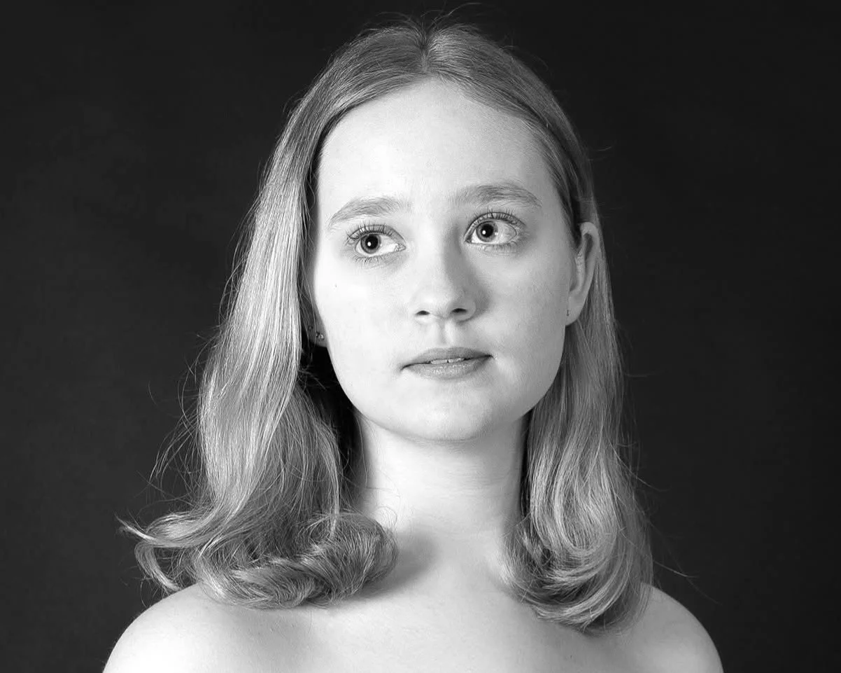 Black and white portrait of a young woman with shoulder-length wavy hair, looking slightly to her left.