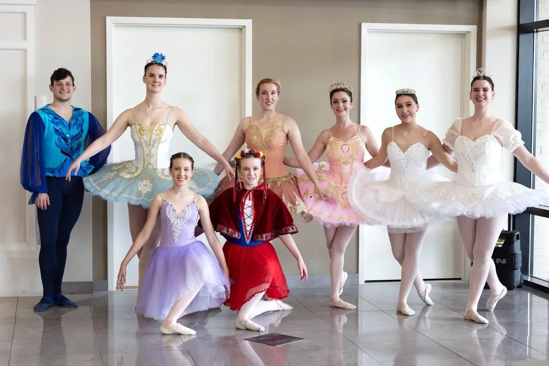 Group of ballet dancers in colorful costumes posing indoors