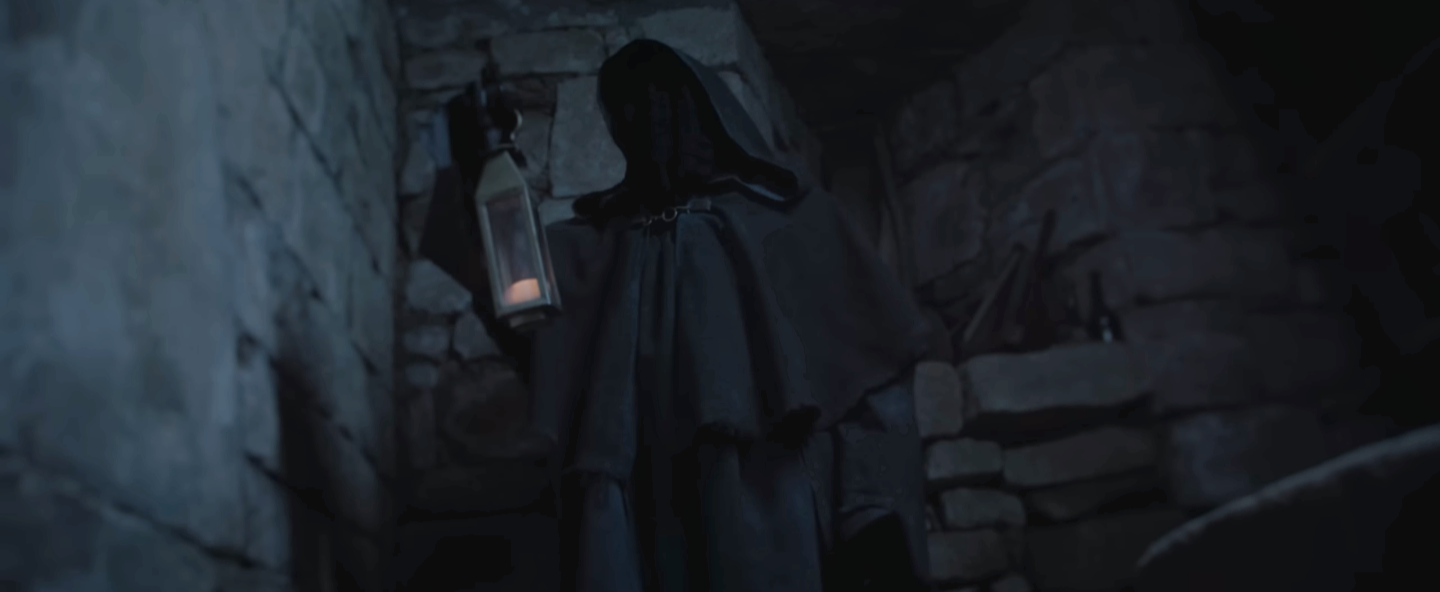 Une silhouette sombre vêtue d'une cape noire, portant un chapeau pointu, dans une pièce sombre en pierre, tenant une lanterne allumée.