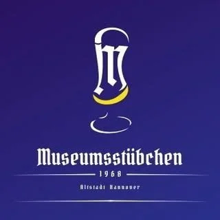 Ein Logo eines Bierglases mit Schriftzug 'Museumsstübchen' und '1968' darunter, auf dunkelblauem Hintergrund.