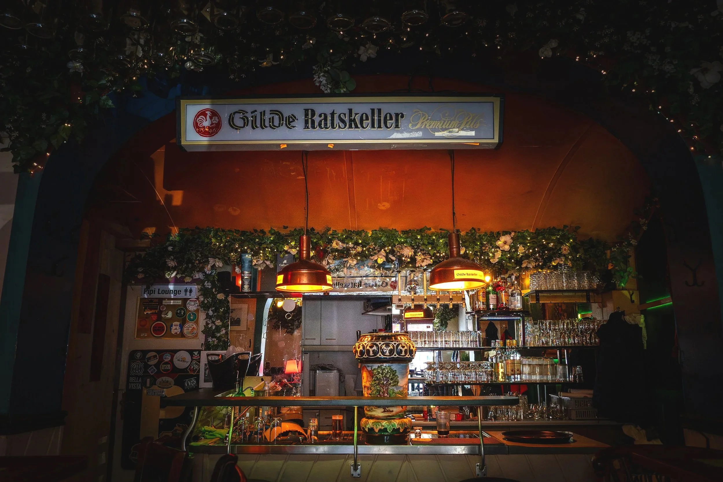 Ein Blick auf eine Bar im Restaurant Gilde Ratskeller bei Nacht, mit Lichterketten, Gläsern und Dekorationen.
