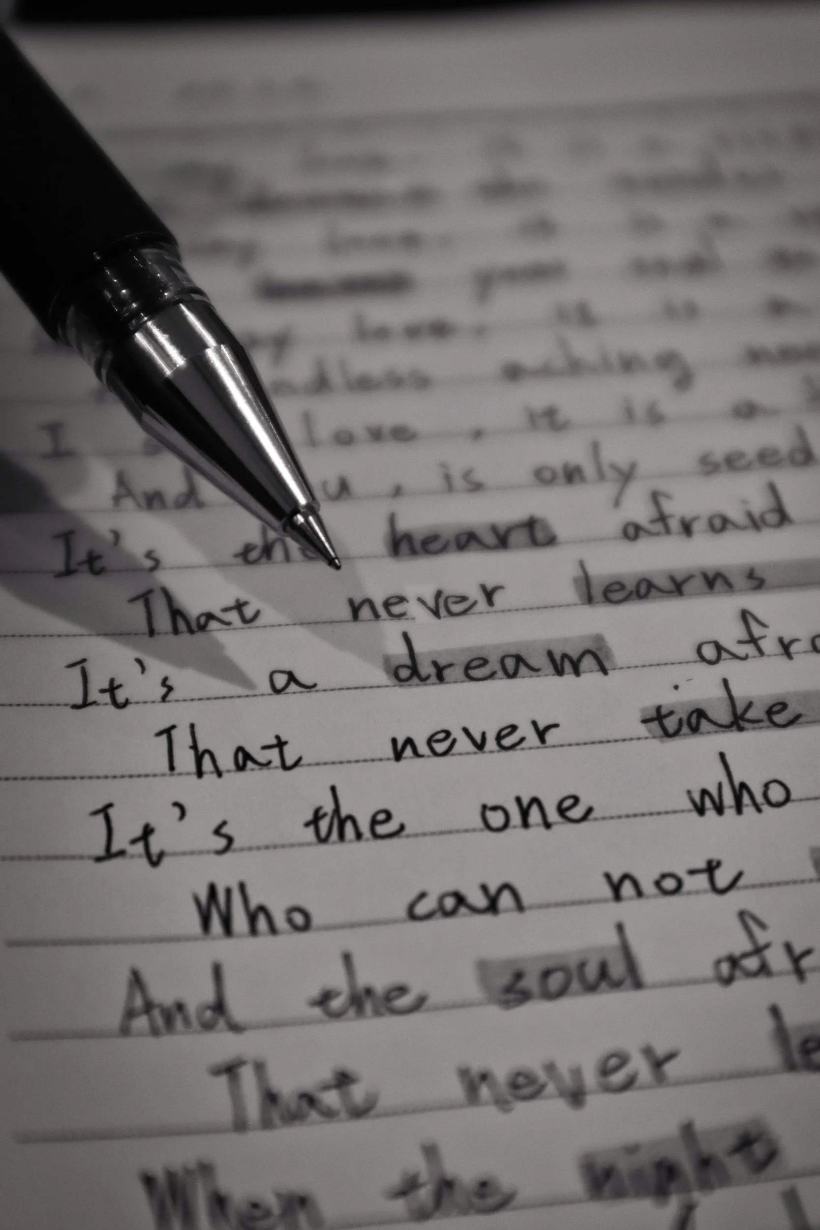 Close-up of handwritten text on lined paper with a black and silver pen resting on it.