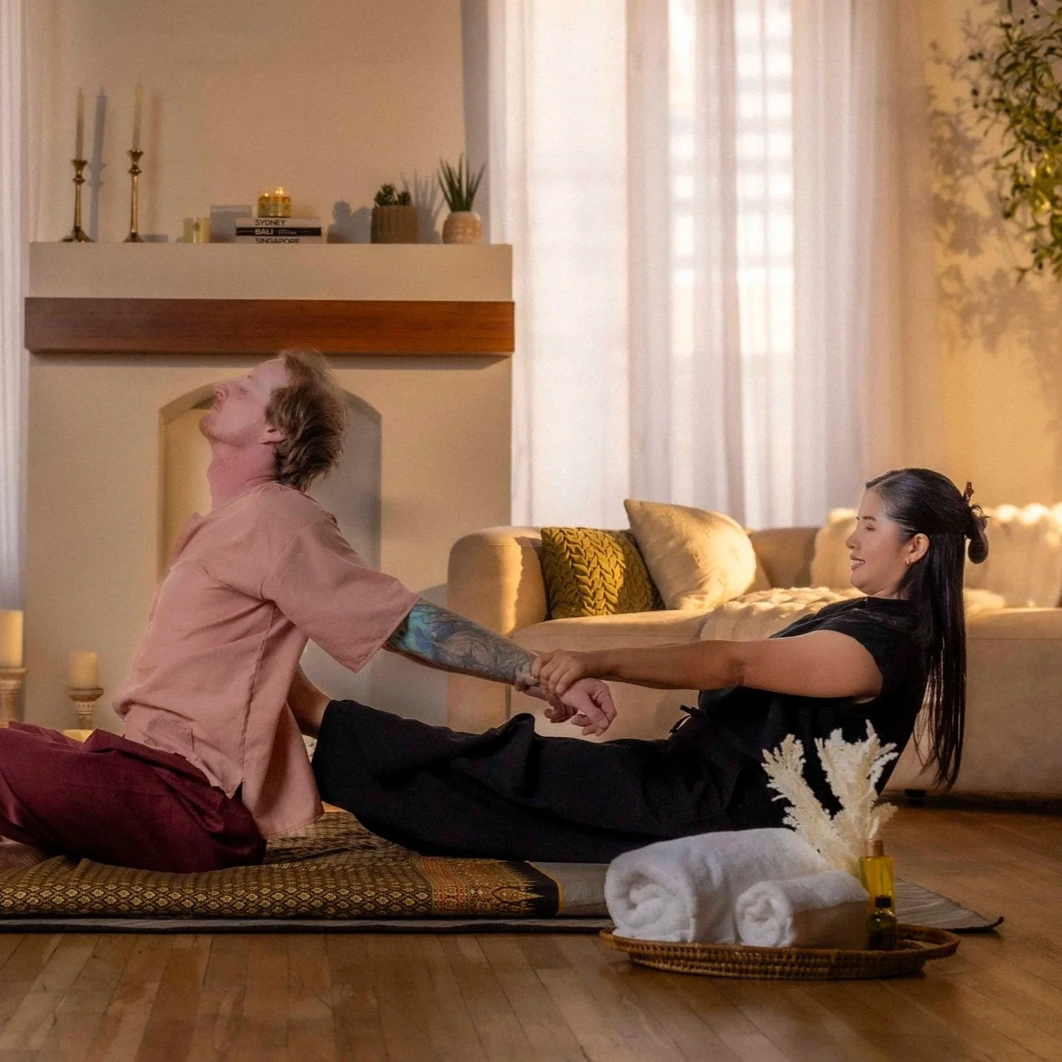 Thai massage therapist applying assisted stretching technique to a client on a floor mat during a mobile session in Arizona