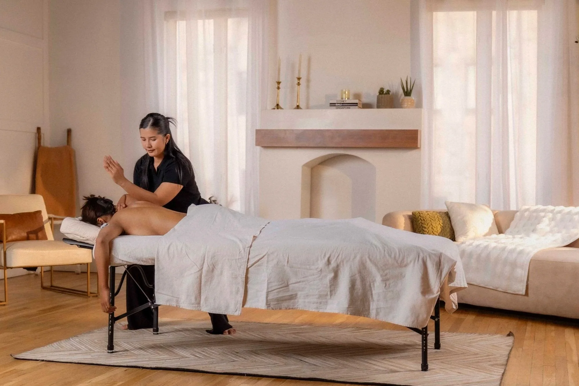 Therapist performing deep tissue massage on client's back on a draped table during session.