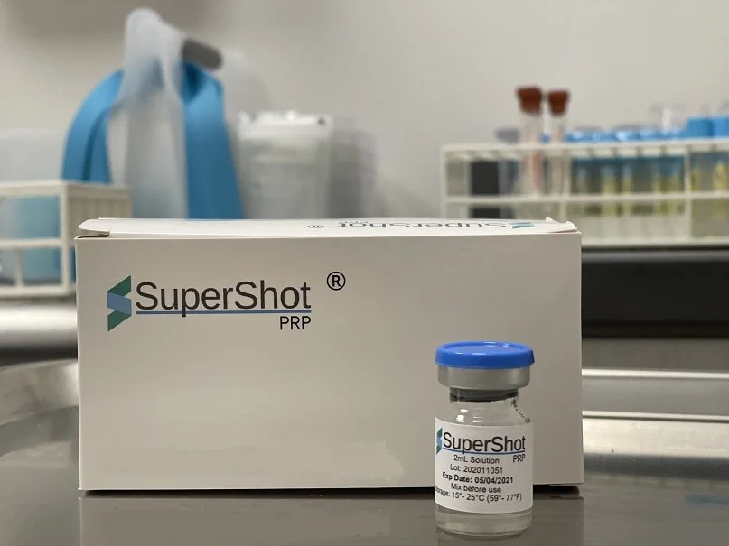 A box of SuperShot PRP with a small vial in front of it, both labeled SuperShot, on a laboratory bench in a laboratory setting.