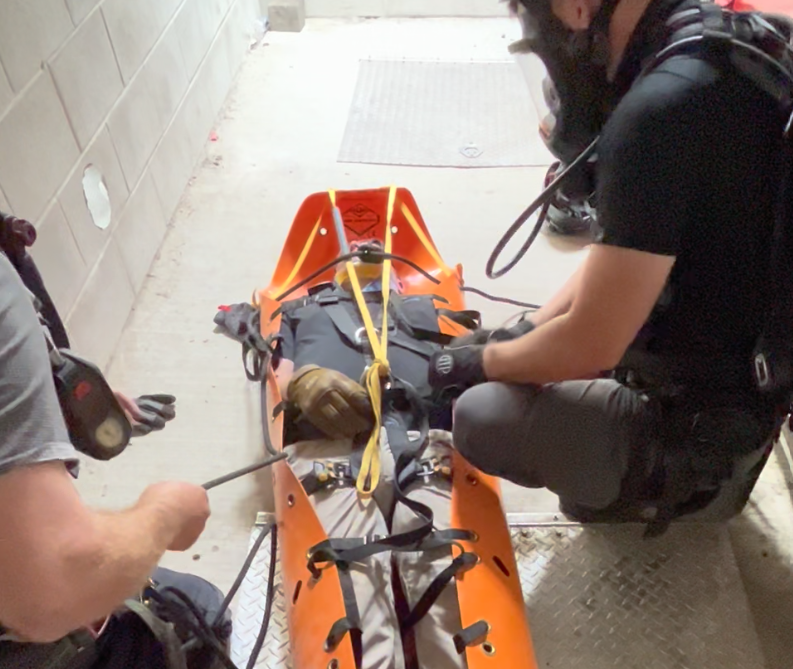 Emergency responders handling a patient on a stretcher in a hospital or emergency setting.