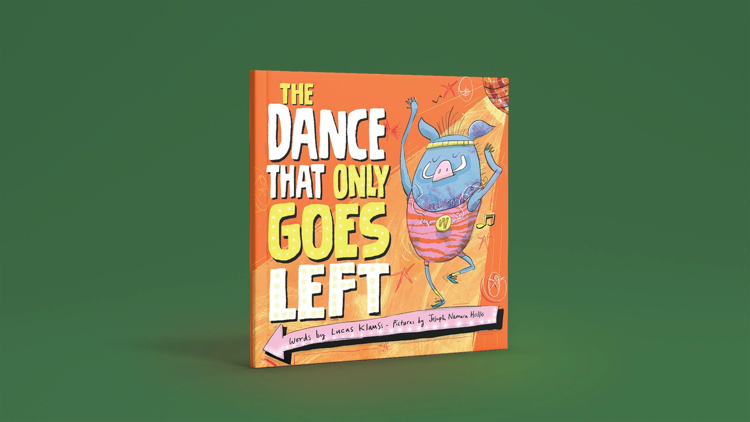 A picture book with an orange cover, featuring a warthog wearing a unitard and sweatband, dancing. The title reads 'THE DANCE THAT ONLY GOES LEFT' written in white and yellow text. The book is placed on a green surface.