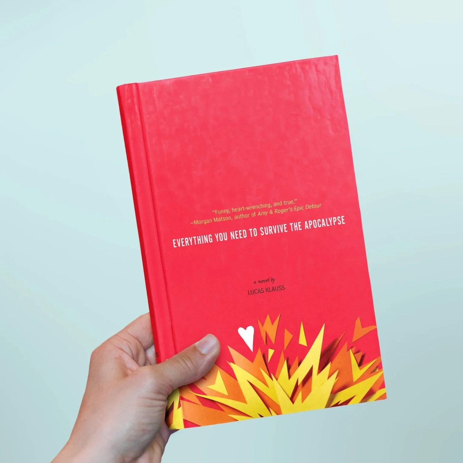 A person holding a red book titled "Everything You Need to Survive the Apocalypse" by Lucas Klauss. The cover features an illustration of an explosion with flames.