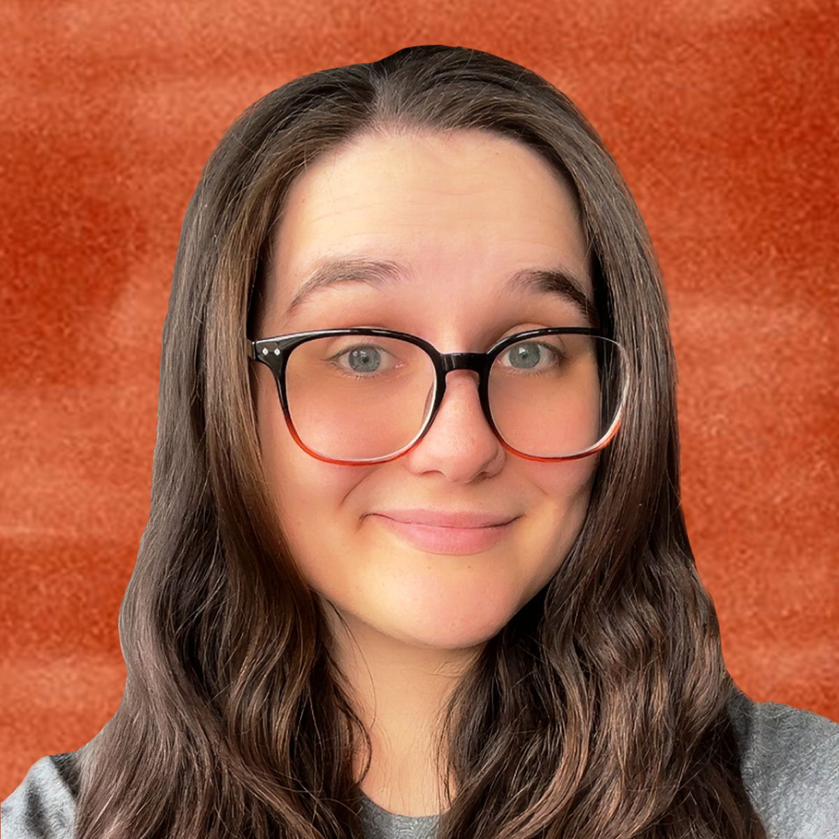 A woman with long wavy brown hair, wearing black and red glasses, smiling in front of a textured orange background.