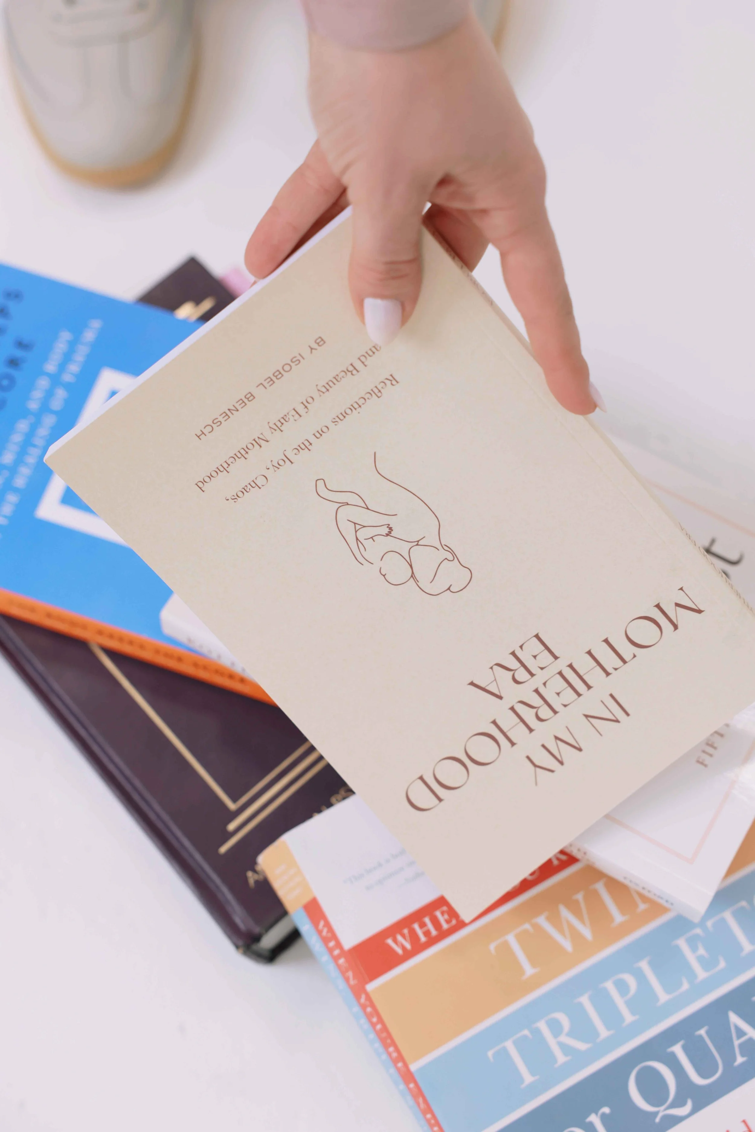 Close-up of a hand flipping through a selection of books or pamphlets on a white surface, with various colorful covers visible.