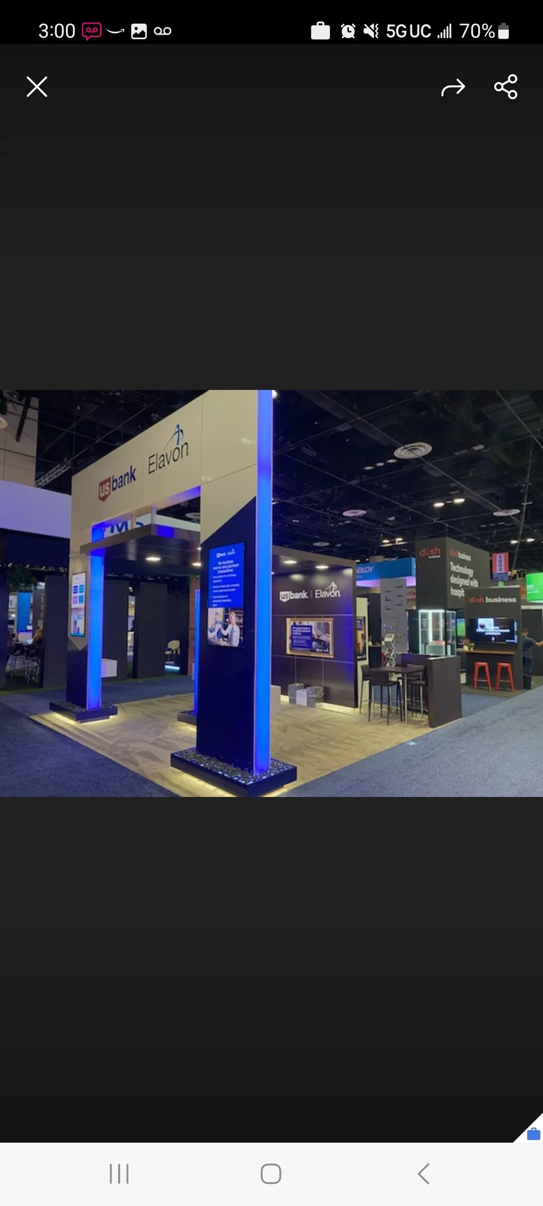Trade show booth for US Bank and Elavon with digital screens, seating area, and signage, illuminated with blue lighting.