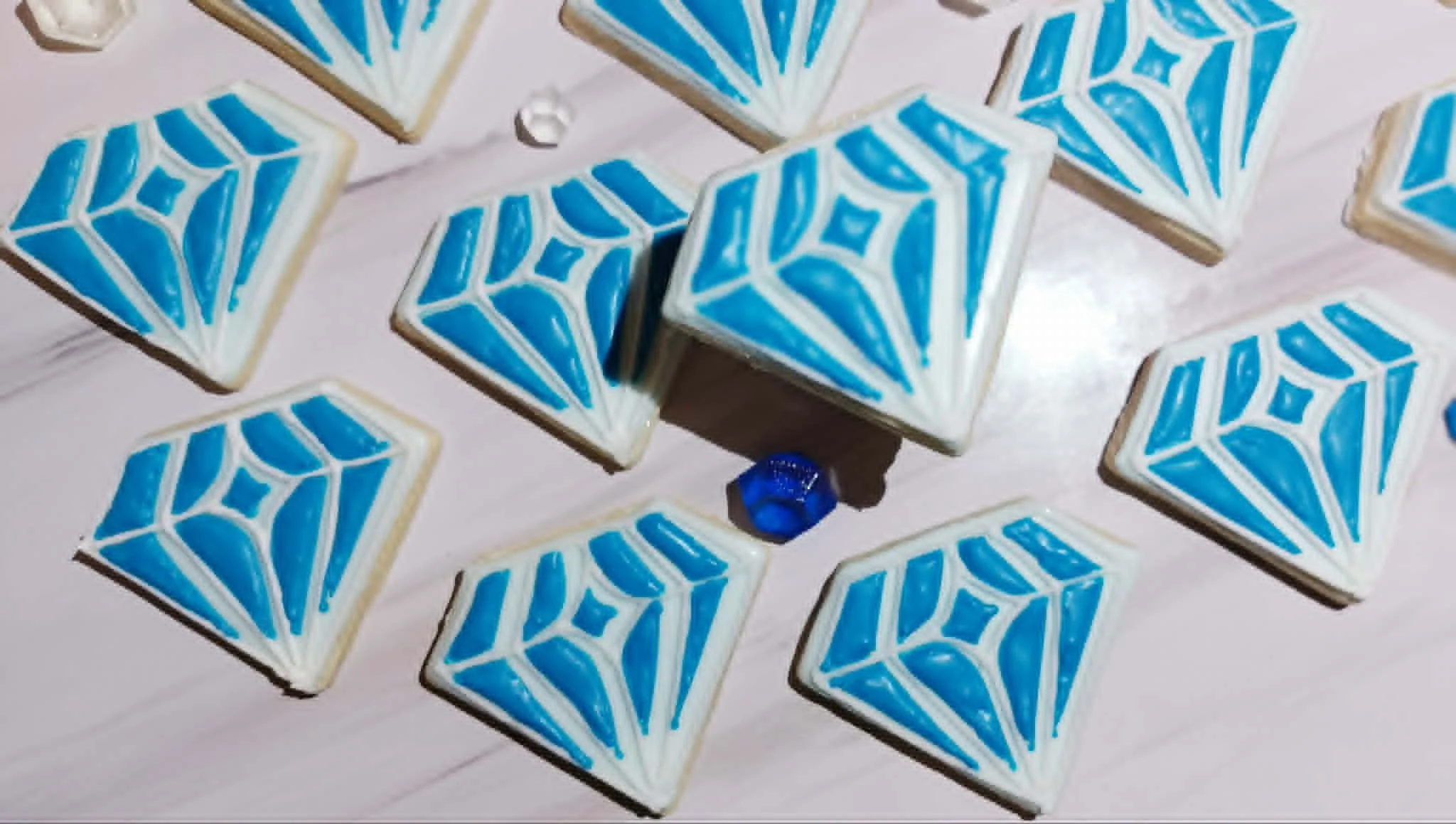 Decorated sugar cookies with blue and white diamond patterns on a white surface.