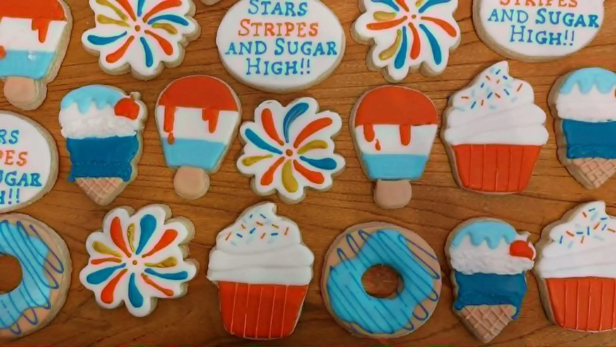 Assorted colorful cookies with patriotic designs, including ice cream cones, fireworks, and donuts.