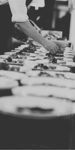 Une personne prépare ou sert des plats dans une cuisine.