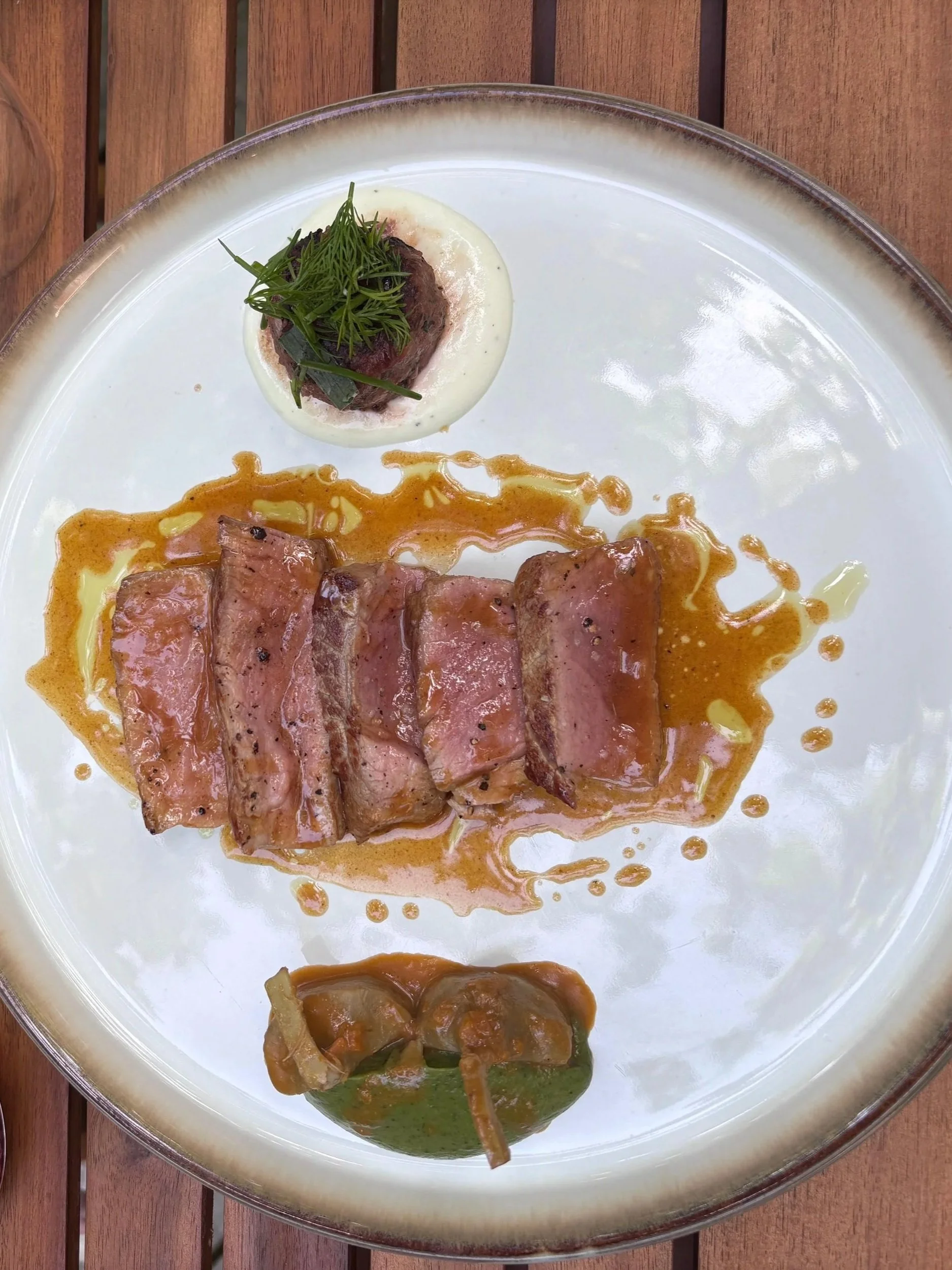 Assiette de viande et légumes, présentation sophistiquée, avec garnitures et sauces, sur un plateau en verre