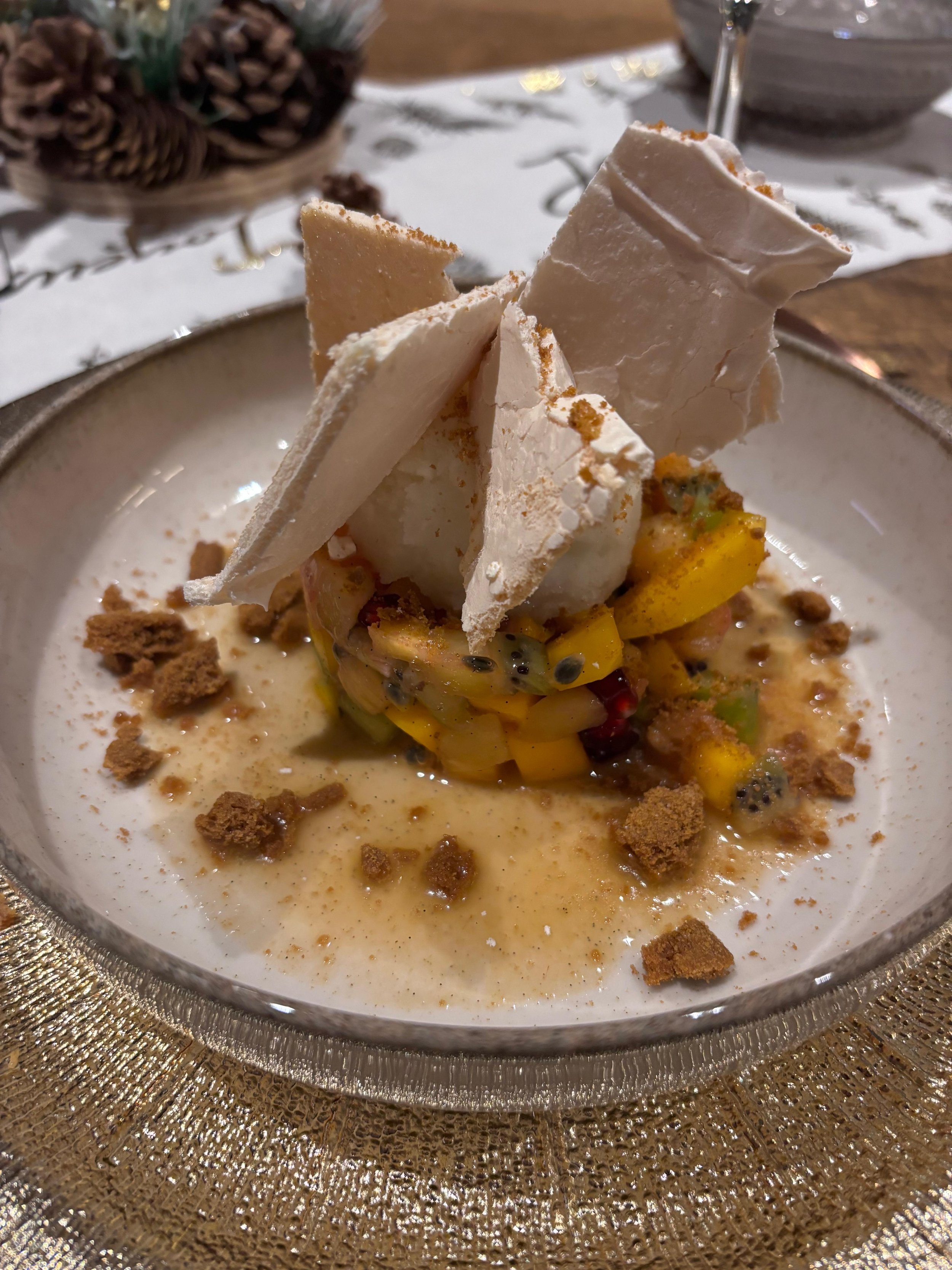 Un dessert crémeux avec des morceaux de fruits et des biscuits, garni de morceaux de meringue et de graines de Passiflora