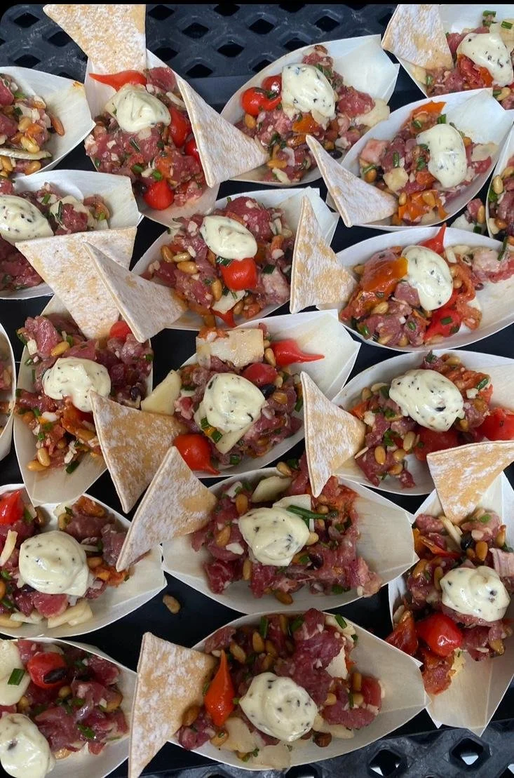 Tacos de carne crue, garnis de crème, tomates cerises, oignons verts, et tortillas croustillantes.