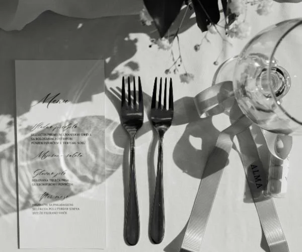 Couverts en argent, verre à vin, menu, fleurs et ruban avec le nom Alina, disposition pour un repas de fête ou mariage.